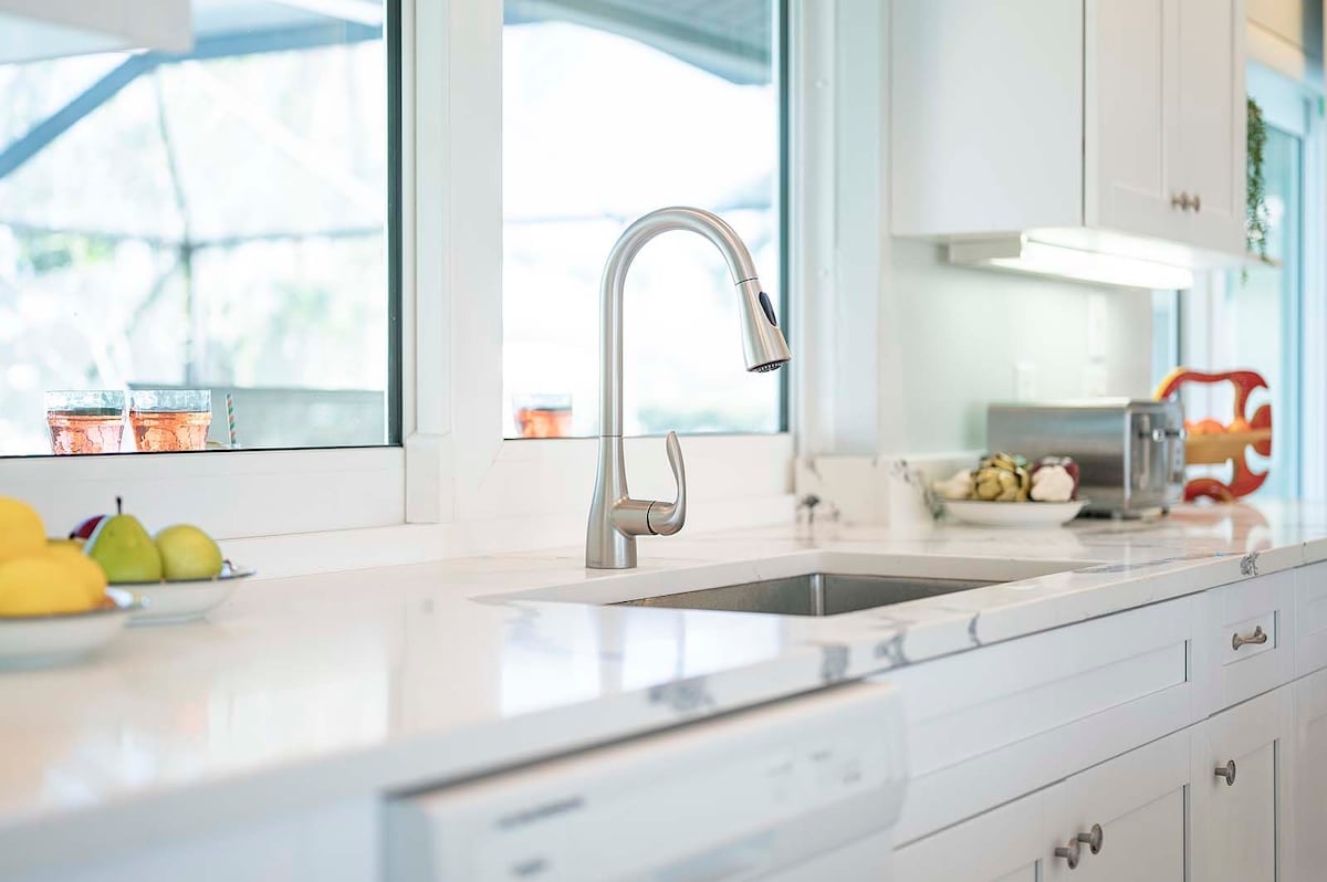 Beheizter Pool mit Blick auf den Kanal und überdachte Veranda mit Grill.