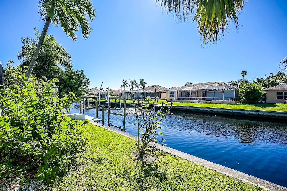 Beheizter Poolbereich mit Sonnenliegen und Blick auf den Kanal mit privatem Dock.