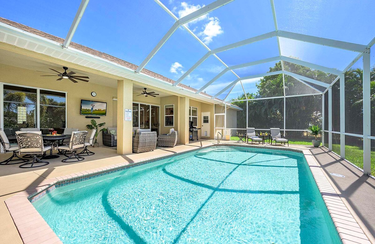 Beheizter Pool mit Sonnenliegen und Blick in den großen, privaten Garten mit Grill.