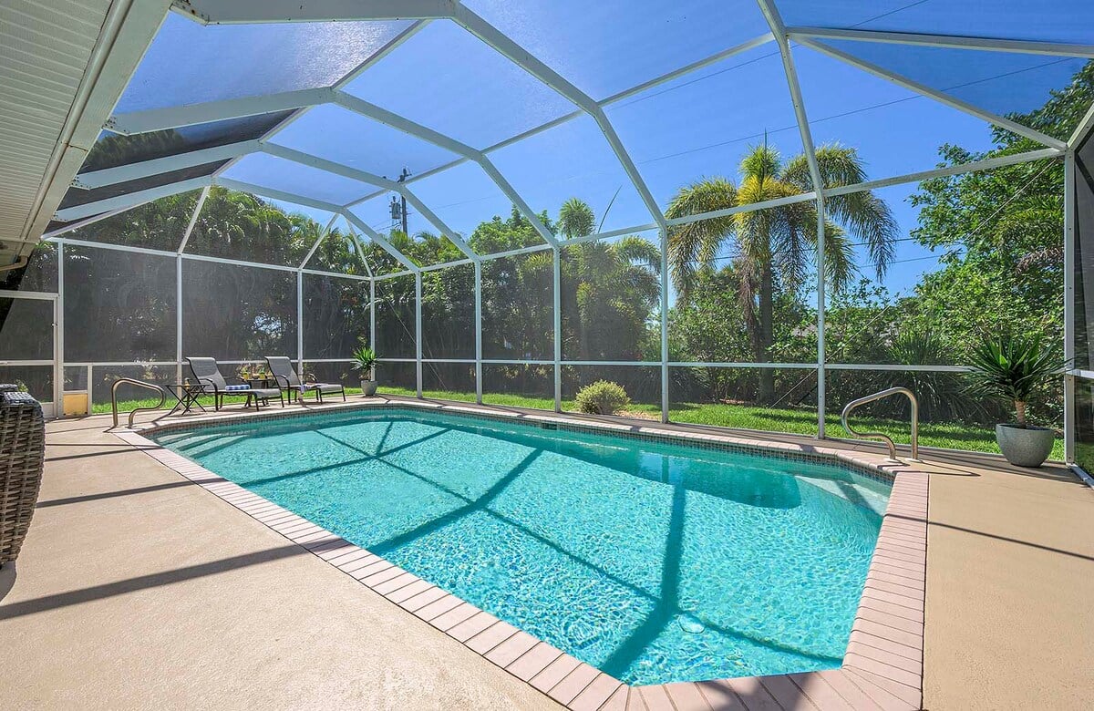 Beheizter Pool mit Sonnenterrasse und Blick in den großen, privaten Garten mit Grill.