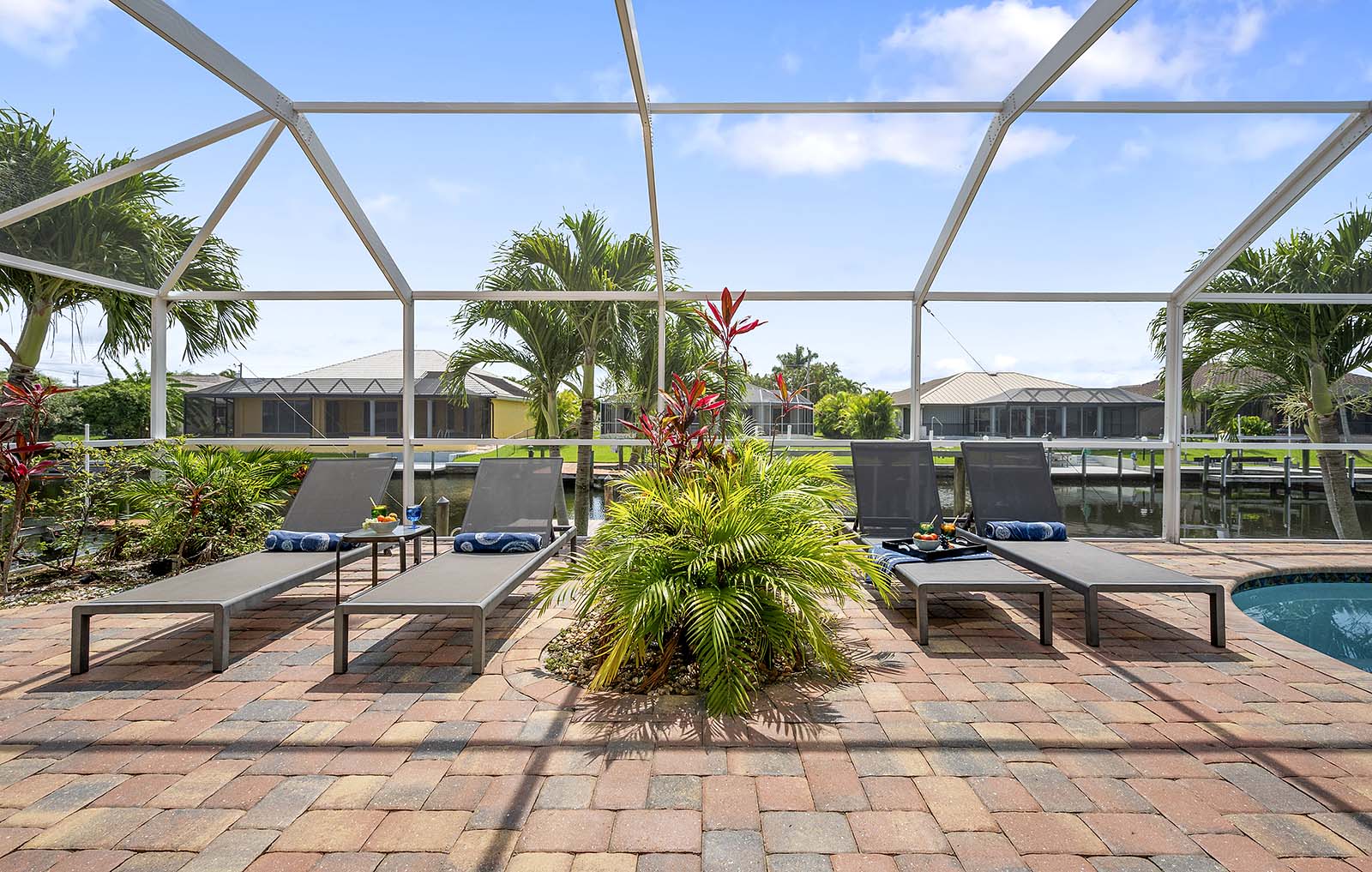 Privater Poolbereich mit Sonnenliegen und Blick auf den Kanal mit Bootsdock.