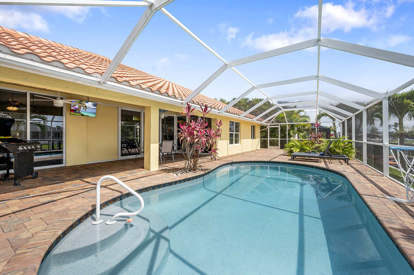 Privater Poolbereich mit Sonnenliegen und TV am Kanal.