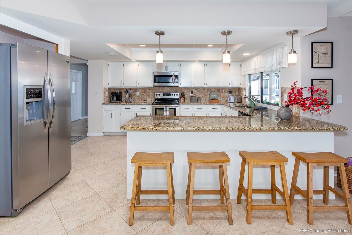 Überdachte Lanai mit Esstisch und Blick auf Pool und See.