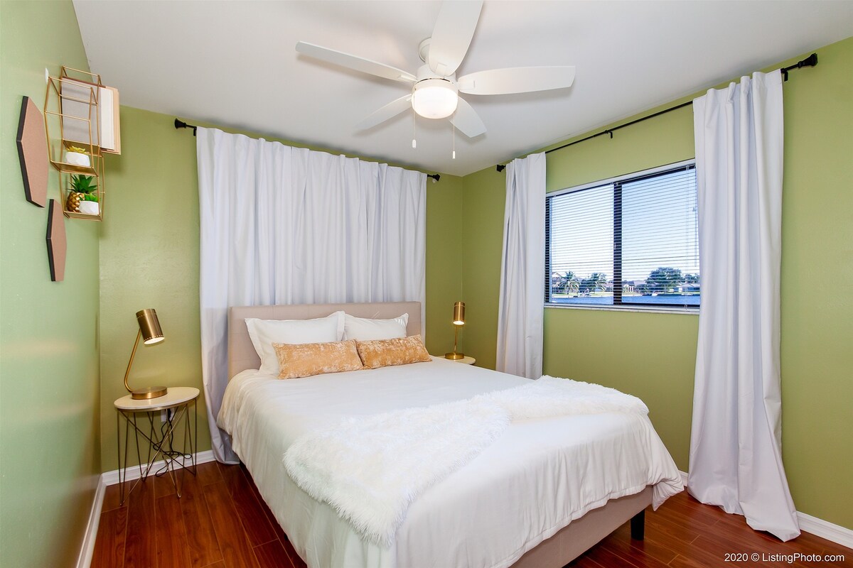 Überdachte Lanai mit Esstisch und Blick auf Pool und See.