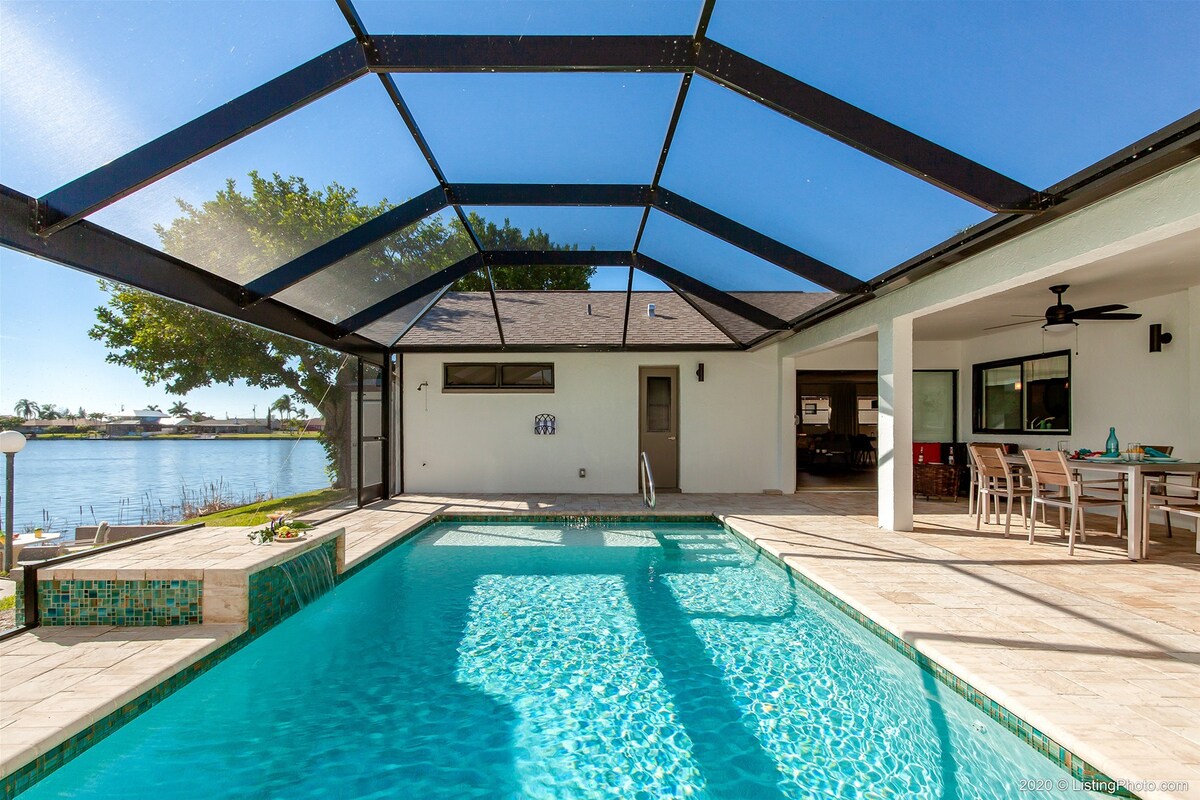 Überdachte Lanai mit Esstisch und Blick auf Pool und See.