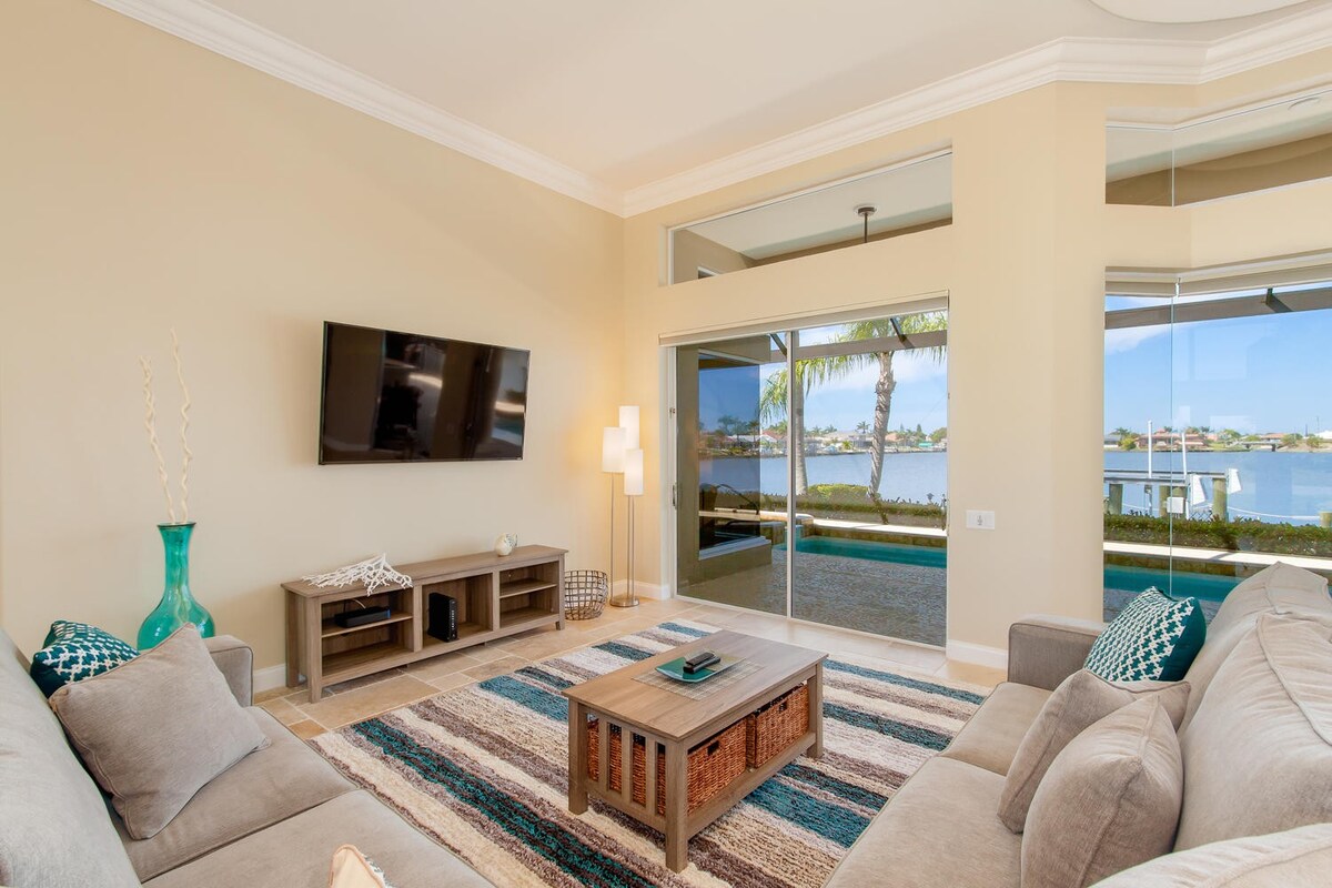 Überdachte Veranda mit Sitzbereich und Blick auf den Kanal bei Sonnenuntergang.