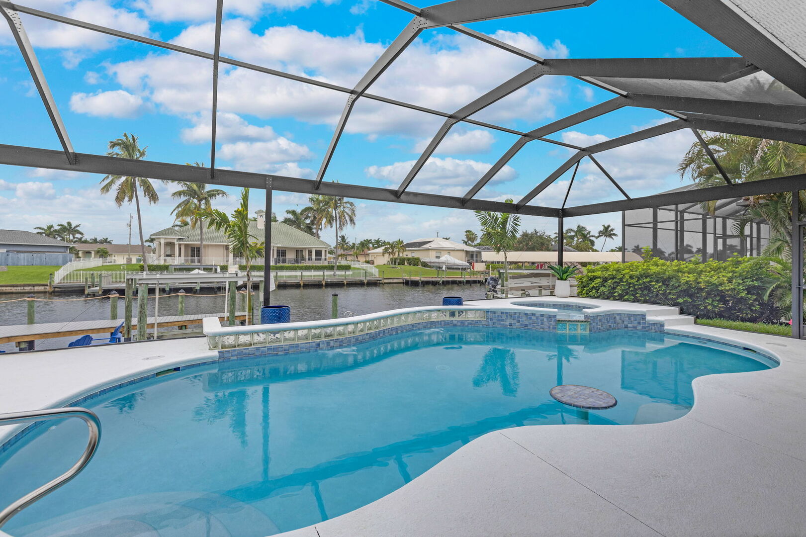 Große Lanai mit Außen-Esstisch, Sonnenliegen und Blick auf den Kanal.