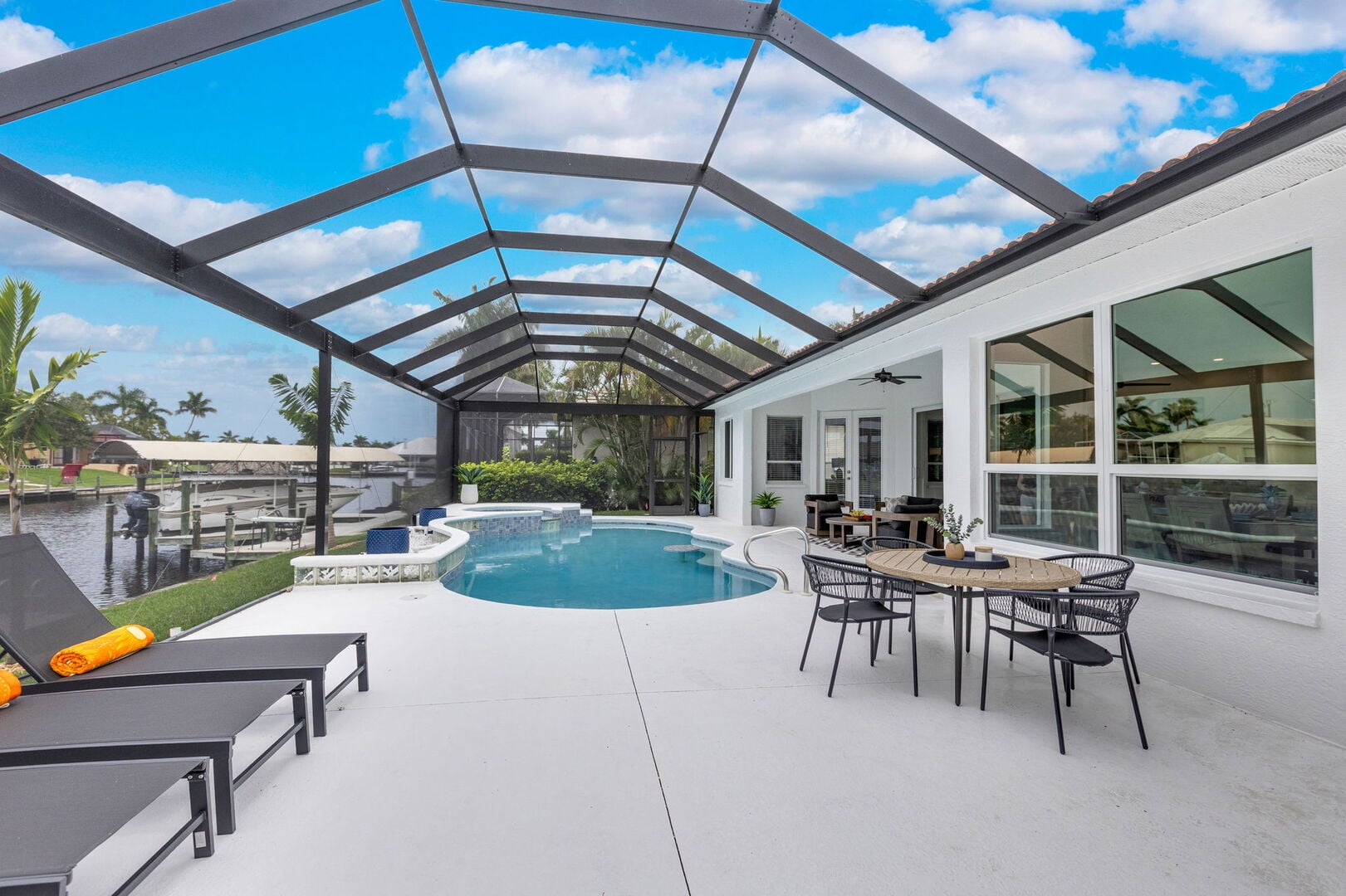 Große Lanai mit Esstisch, Sonnenliegen und Blick auf den Kanal.