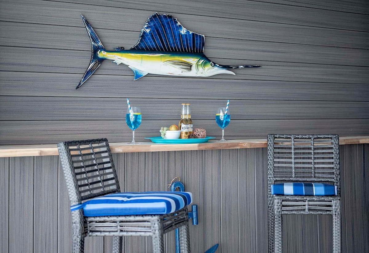 Überdachte Lanai mit Esstisch und Blick auf Pool und Kanal.