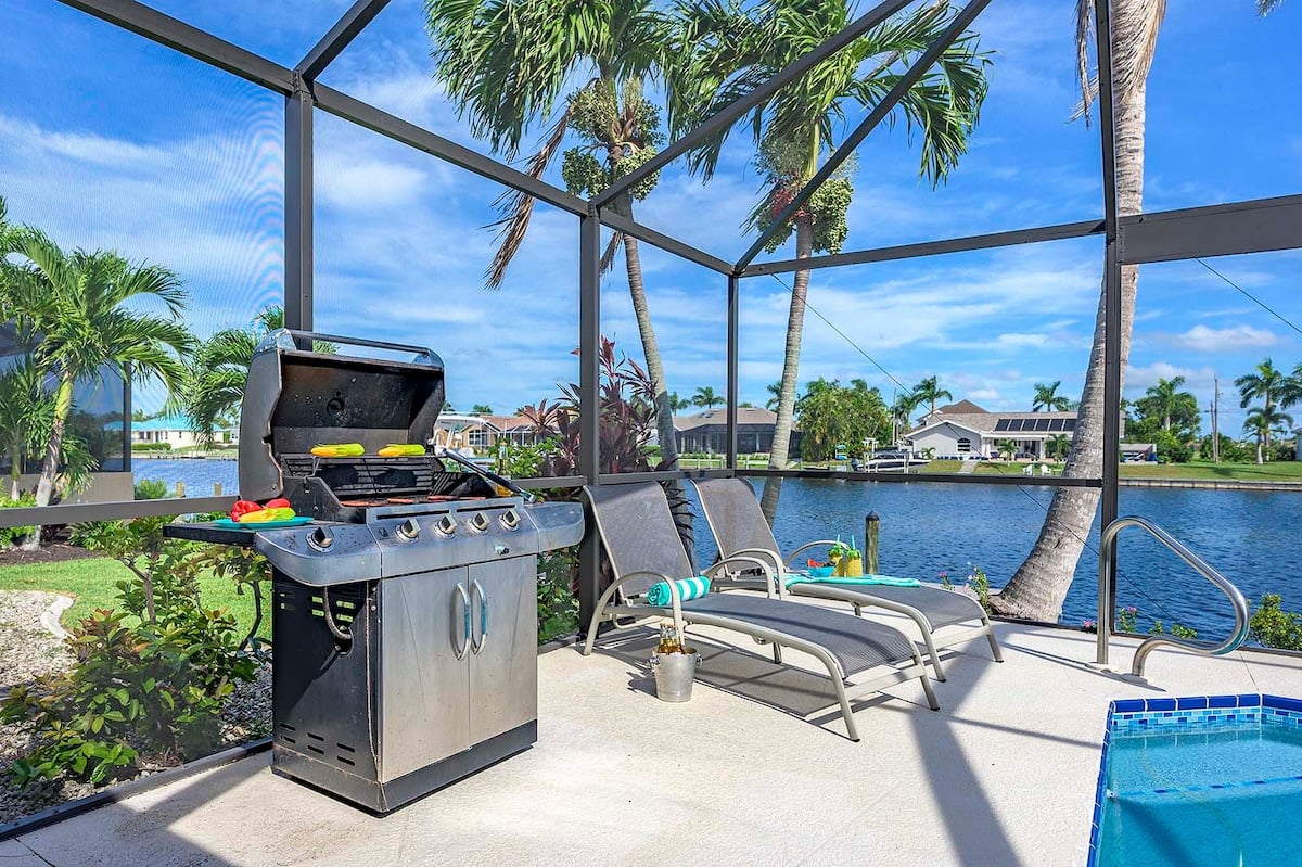 Überdachte Lanai mit Esstisch und Blick auf Pool und Kanal.