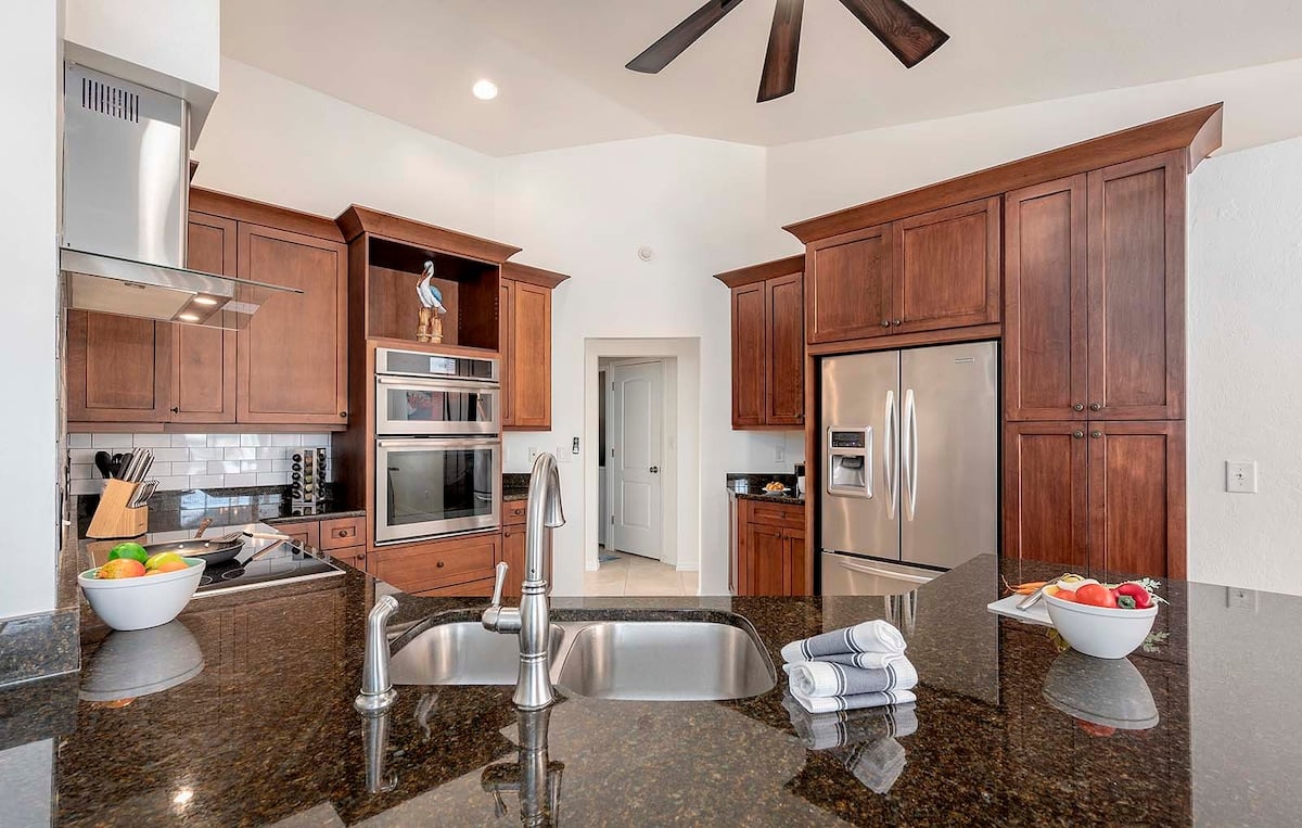 Überdachte Lanai mit Esstisch und Blick auf Pool und Kanal.