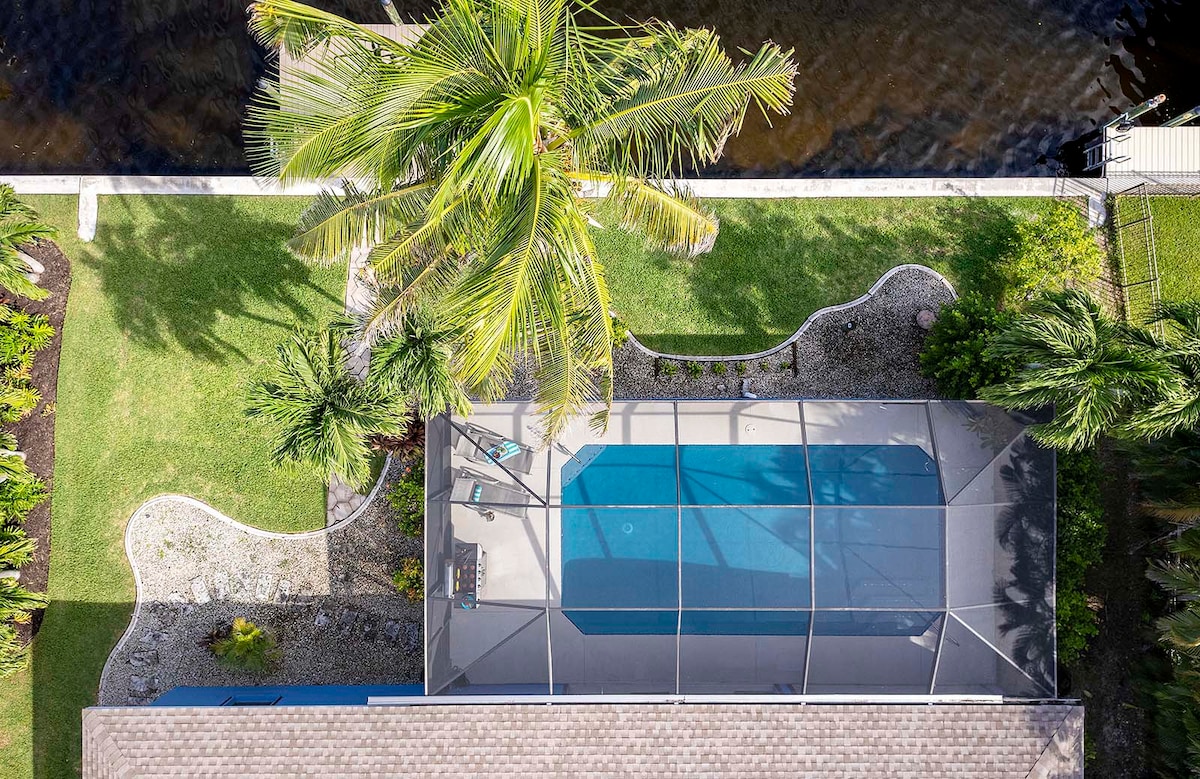 Überdachte Lanai mit Esstisch und Blick auf Pool und Kanal.