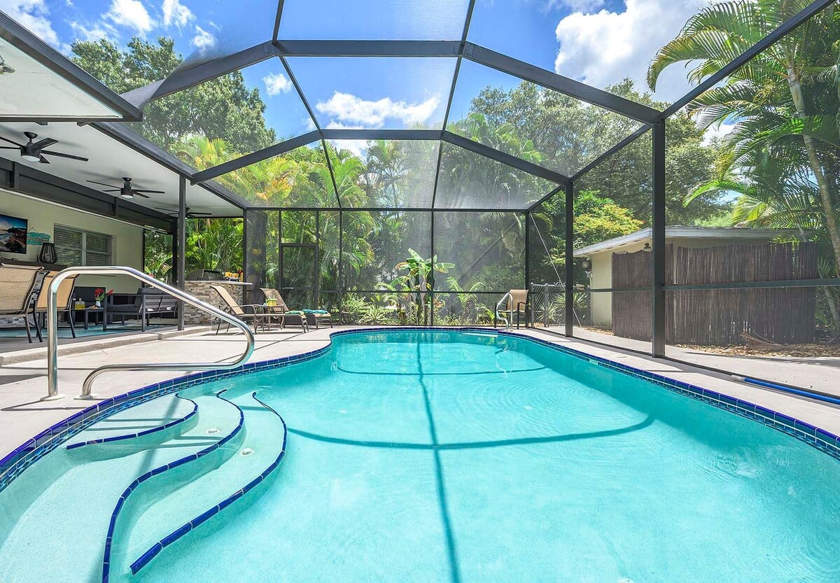 Beheizter Pool mit Sonnenliegen und TV im Außenbereich.