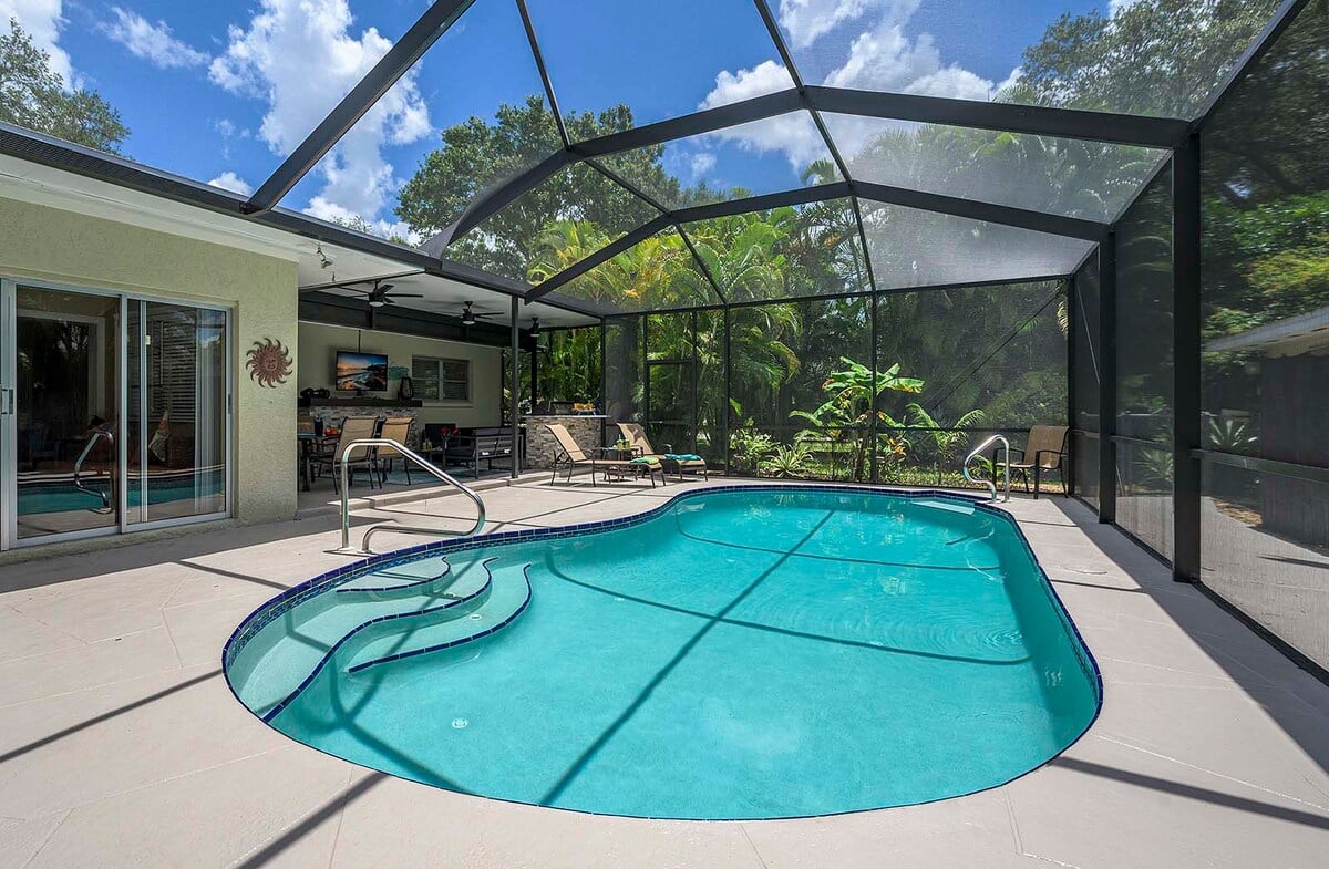 Beheizter Pool mit Sonnenliegen und TV im Poolbereich.