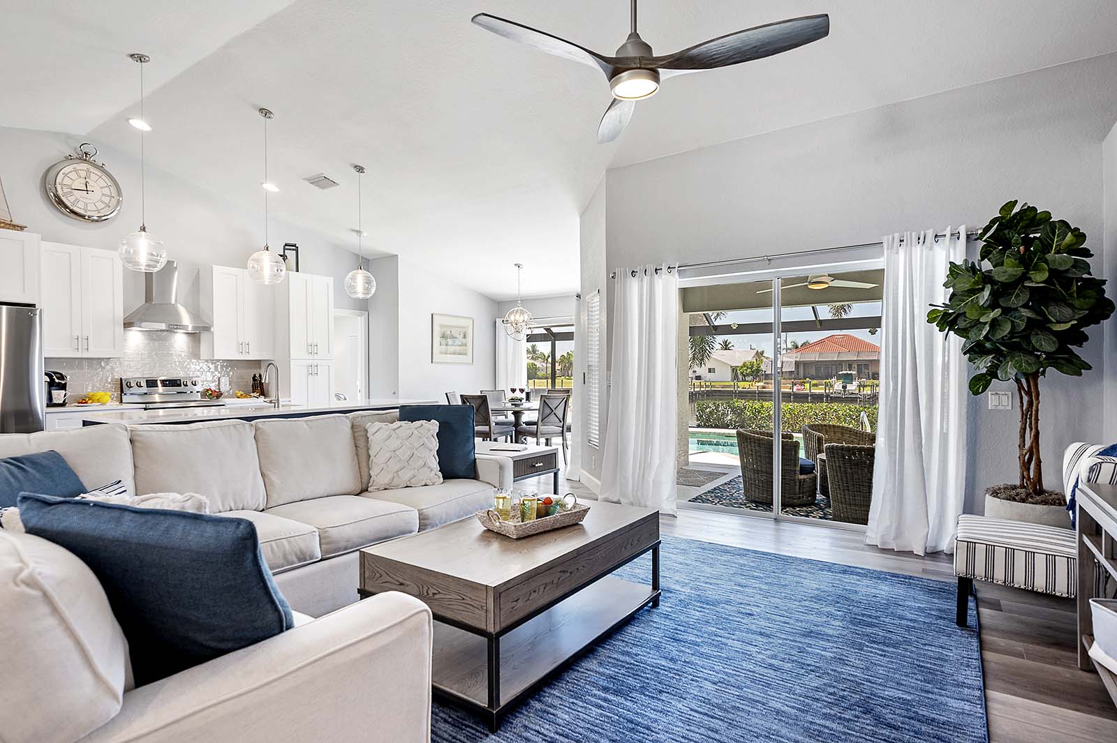 Offenes Wohnen mit bequemer Couch im Wohnzimmer und Blick auf den Pool und die Veranda