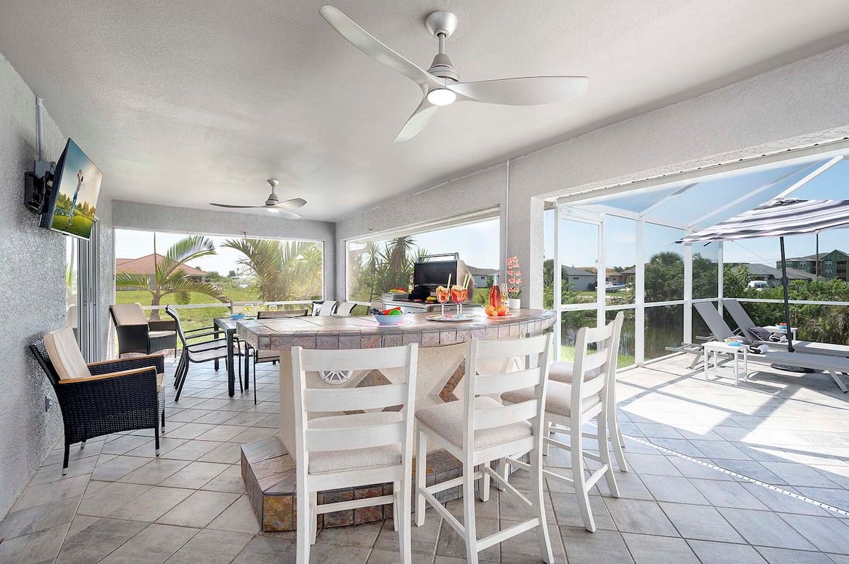 Überdachte Bar im Freien mit TV und Grill sowie Sitzgelegenheiten in der hohen Bar