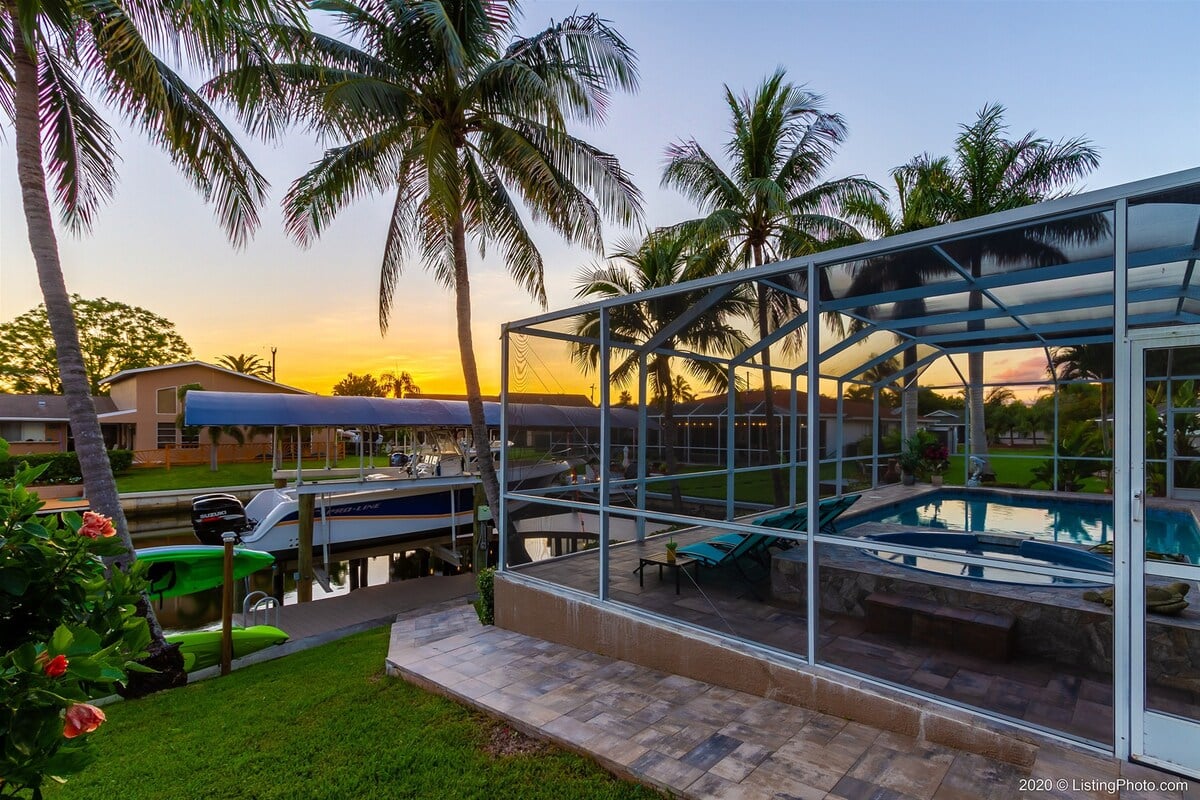 Terrasse am Kanal mit Bootsdock und Kajaks bei Sonnenuntergang.