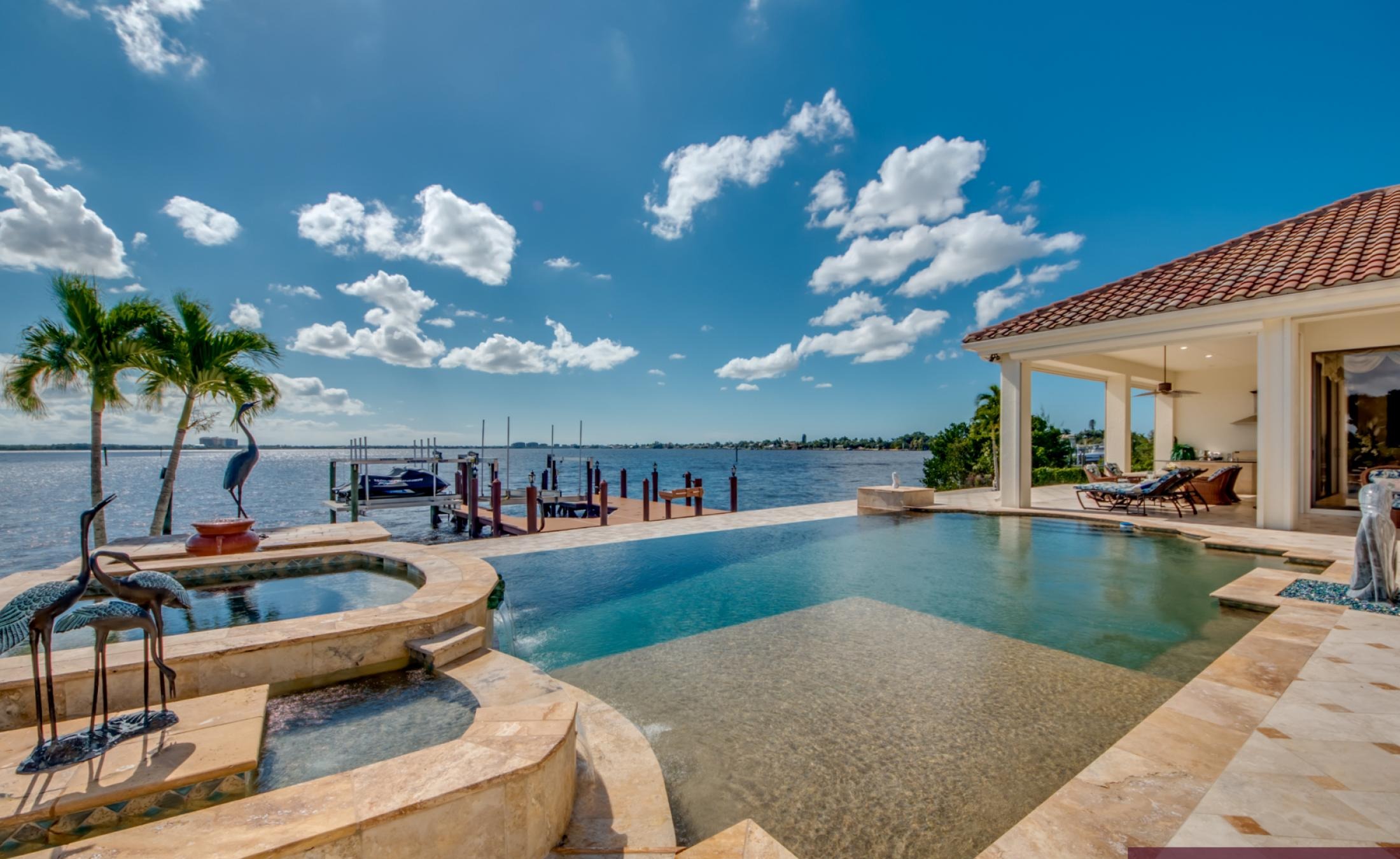 Infinity-Pool mit Spa auf sonniger Lanai, Blick auf den Fluss und Bootsdock.