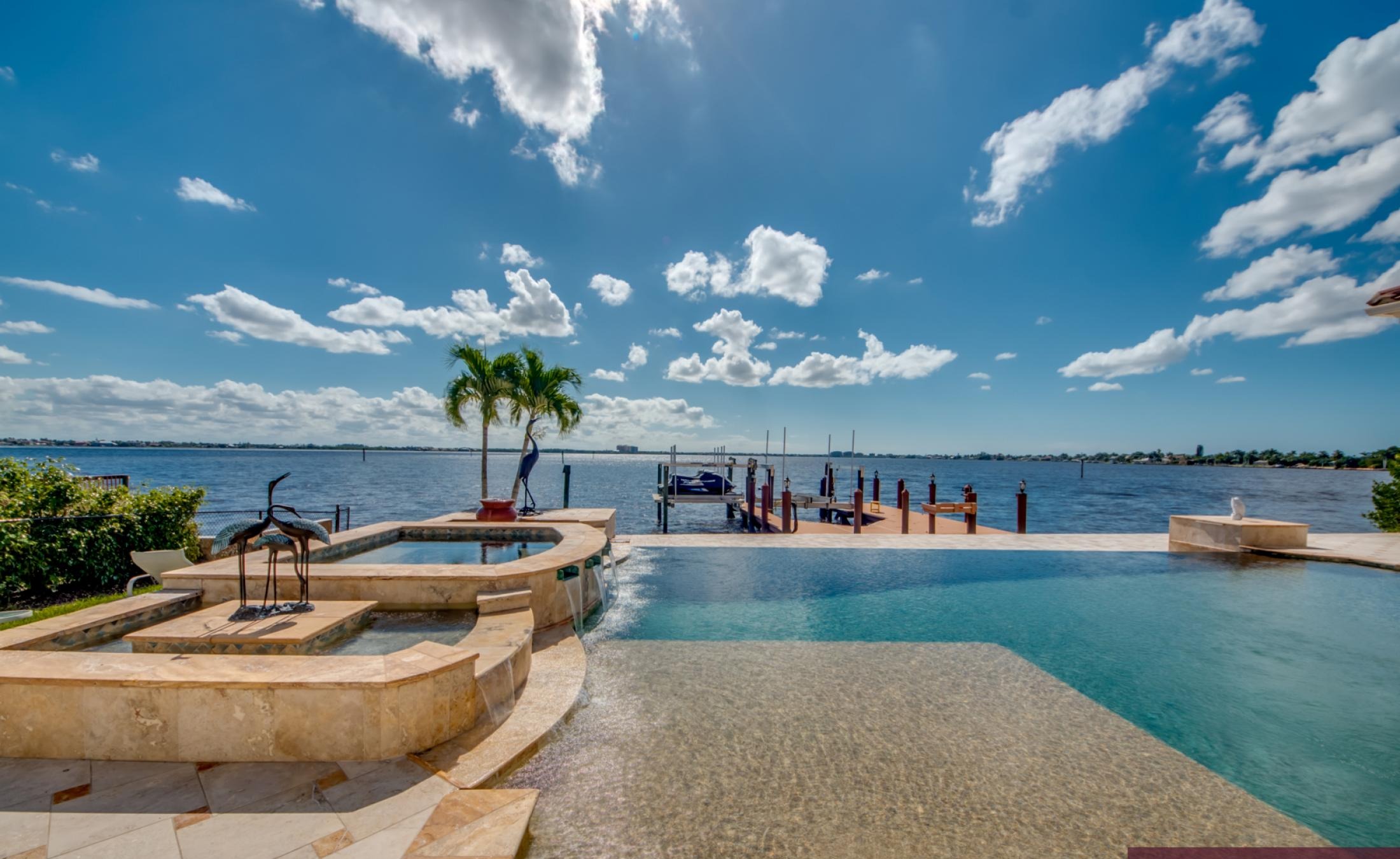Infinity-Pool mit Spa auf der sonnigen Lanai mit Blick auf den Fluss und Bootsdock.