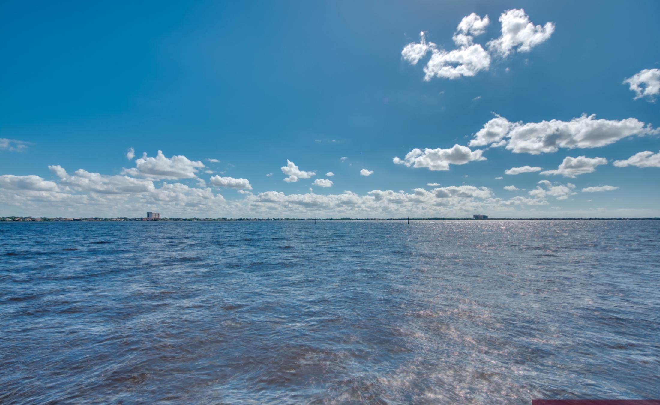 Sonnige Lanai mit Infinity-Pool und Spa am Fluss, Blick aufs Wasser und Bootsdock.