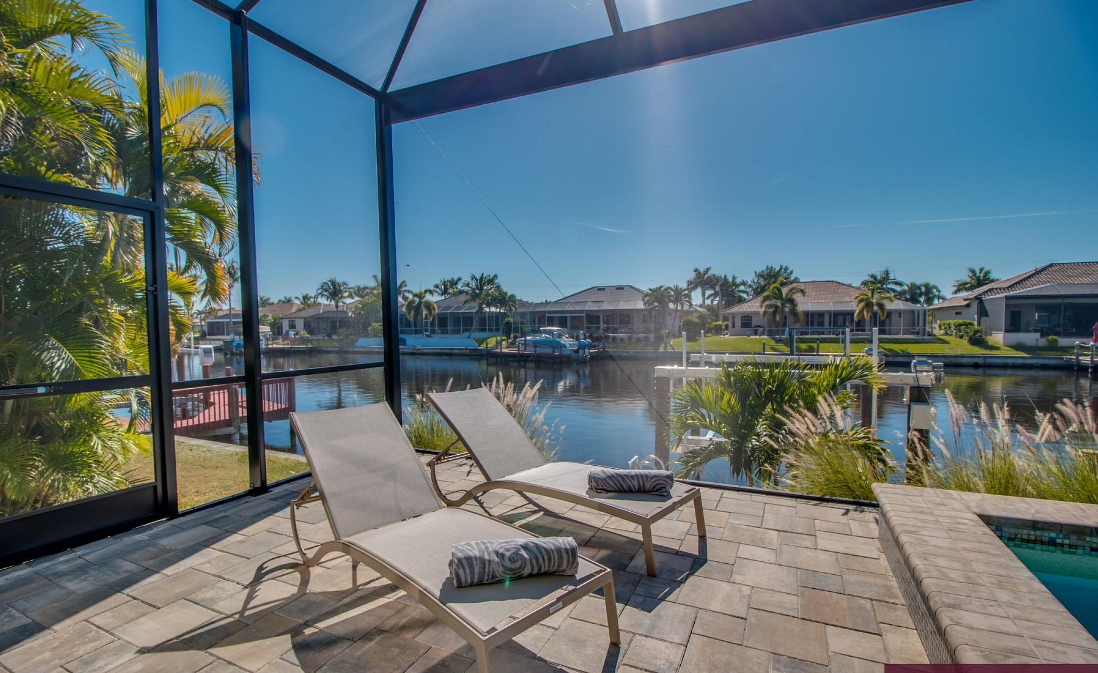 Outdoor-Bereich mit Pool, Spa und Grillplatz am Wasser.