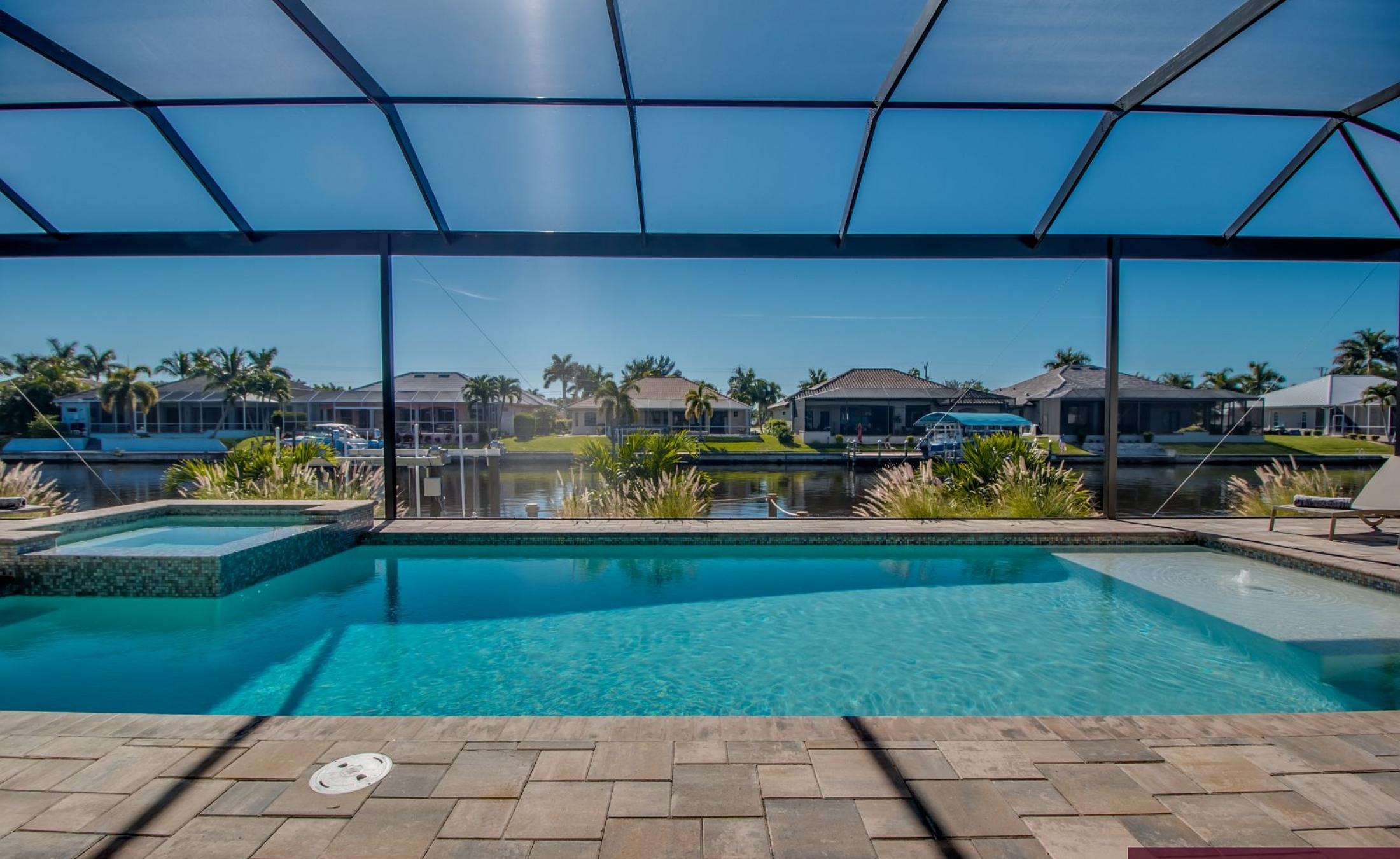 Outdoor-Bereich mit Pool, Spa und Grillplatz am Wasser.