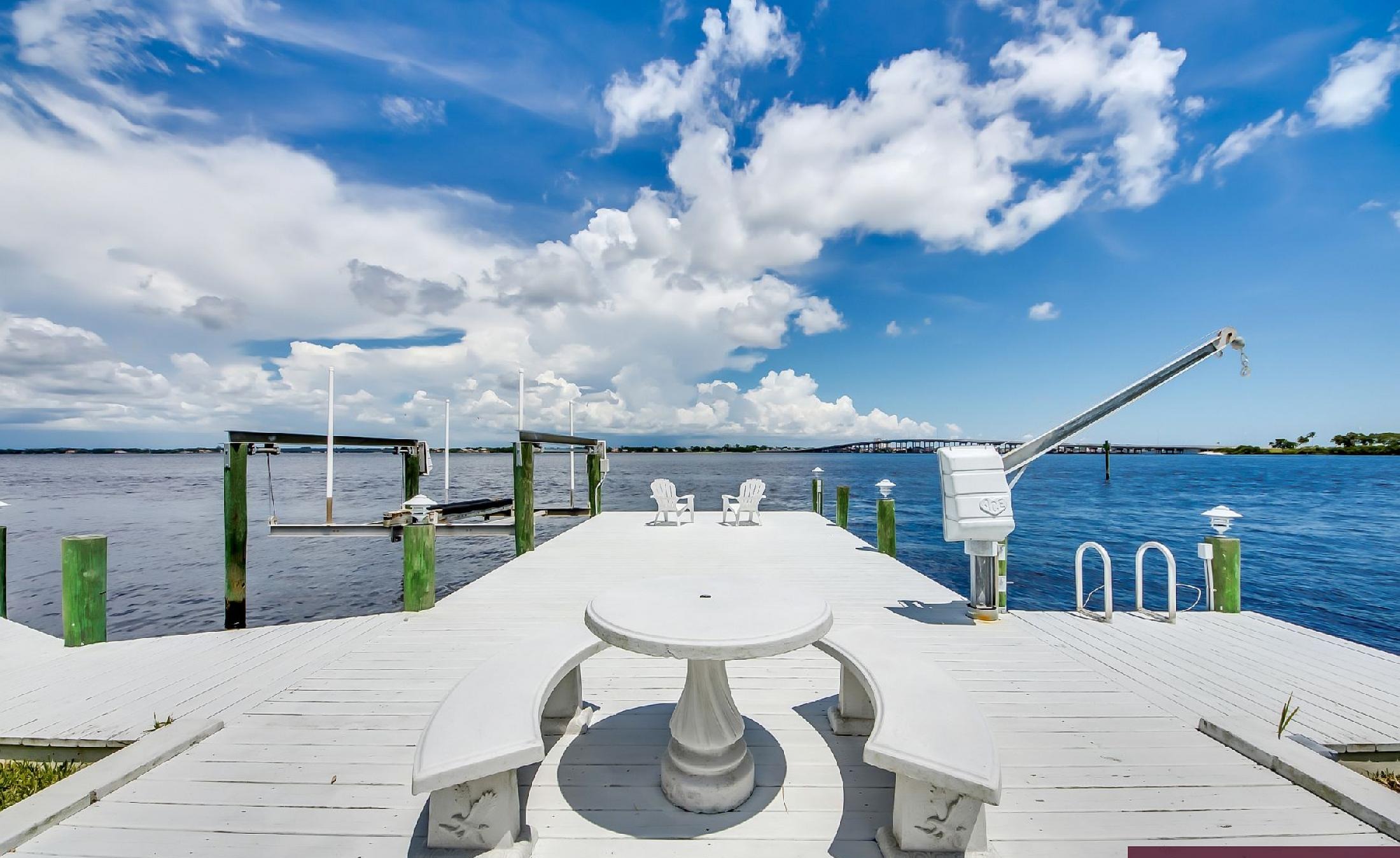 Bootsdock mit Bootslift am Flussufer und weitem Wasserblick.