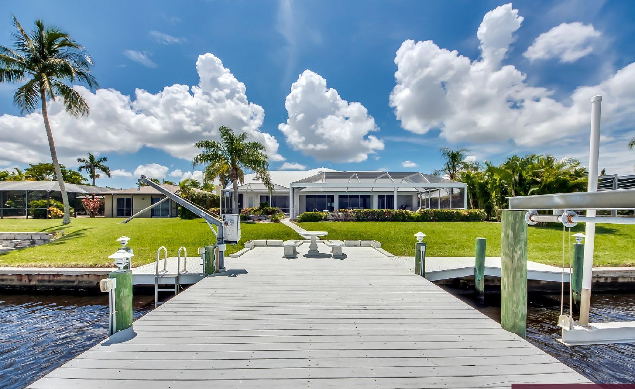 Bootsdock mit Bootslift am Flussufer und weitem Wasserblick.