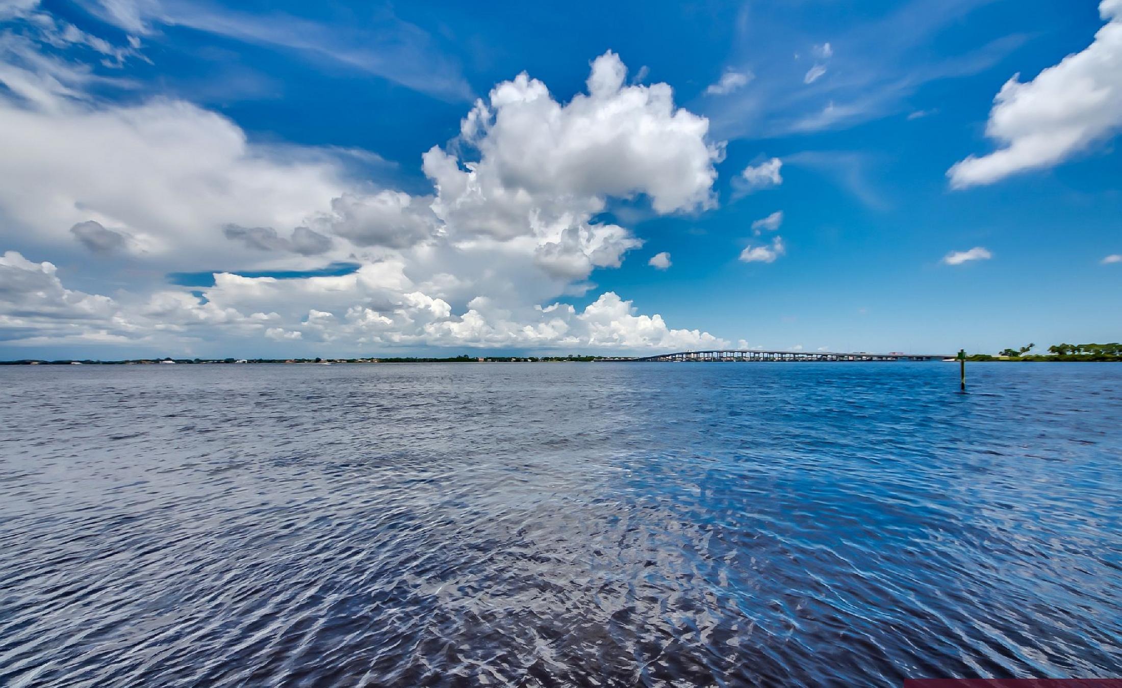 Bootsdock mit Bootslift am Flussufer und weitem Wasserblick.