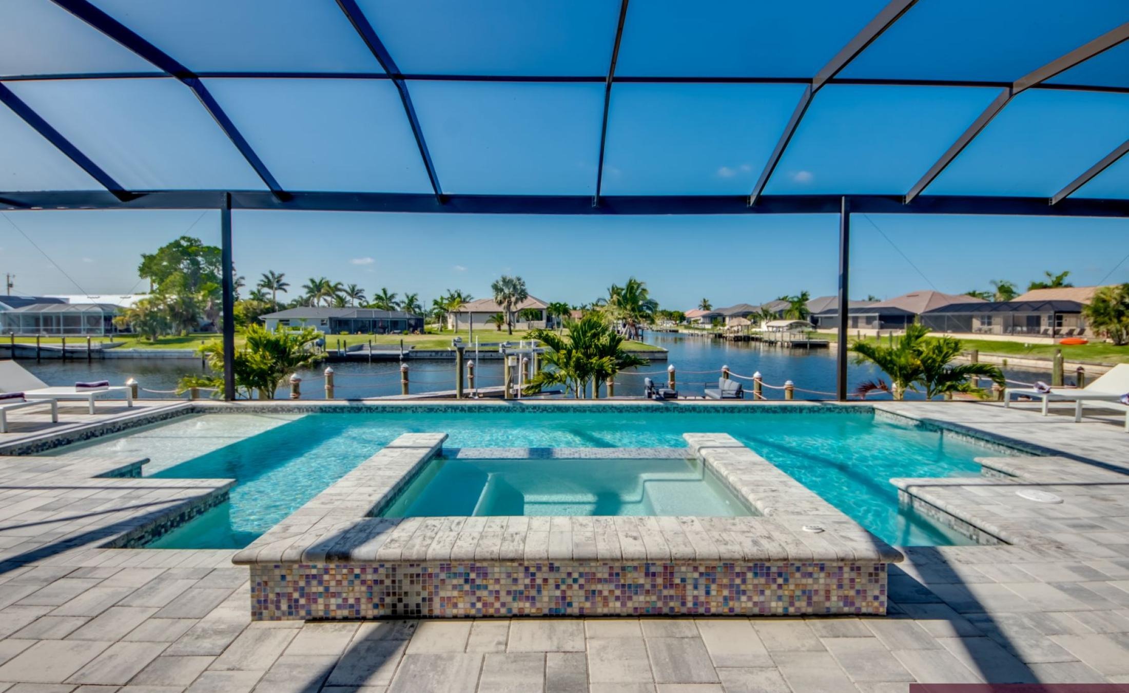 Sonniger Pool- und Spa-Bereich am Kanal mit Bootsdock und Bootslift.