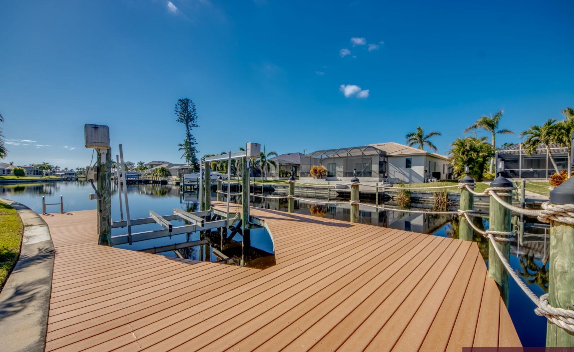 Bootsdock mit Bootslift am Kanal (Gulf Access) bei Sonnenuntergang.