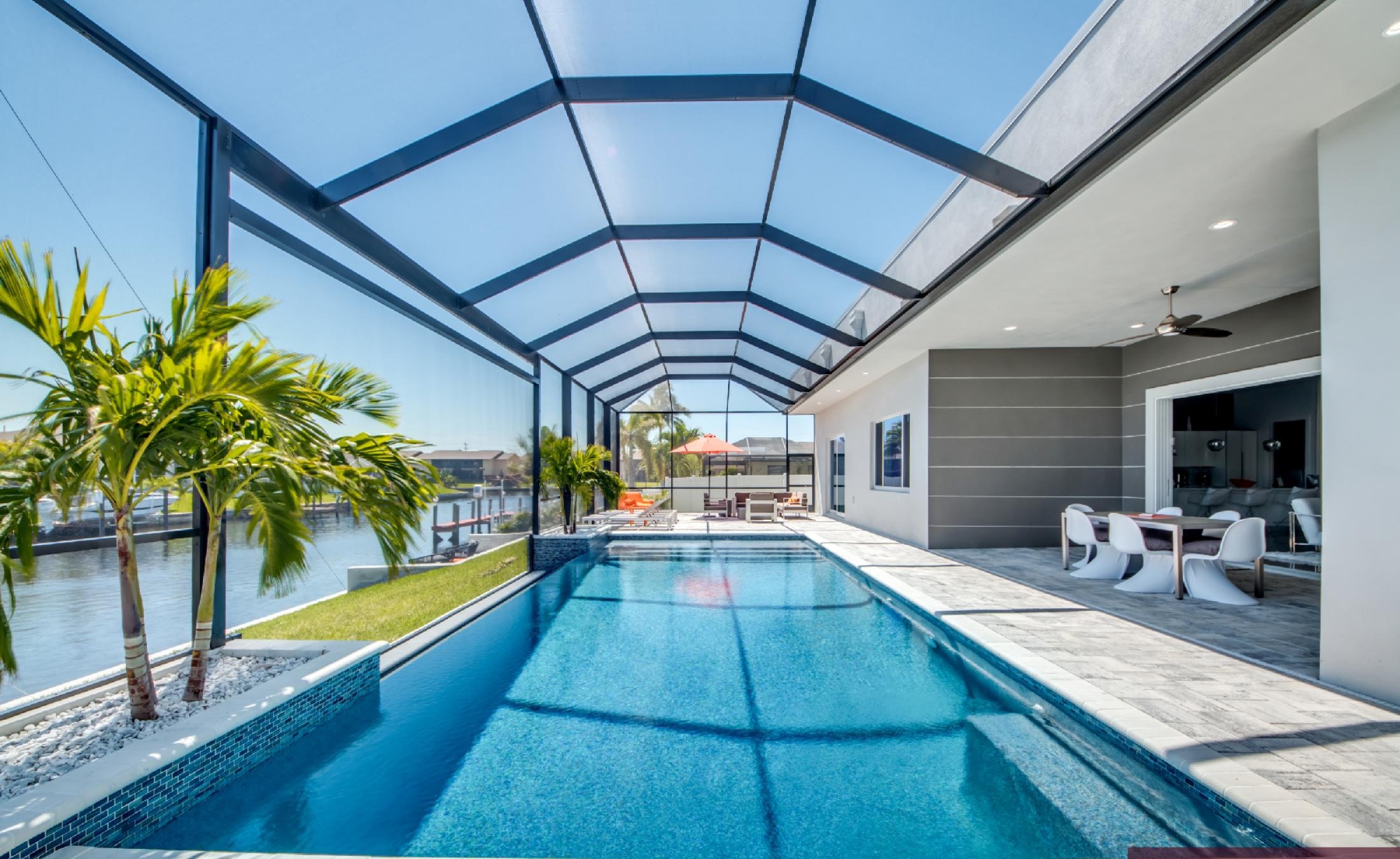 Moderner Poolbereich mit Salzwasser-Infinity-Pool und Blick auf den Kanal mit Bootsdock.