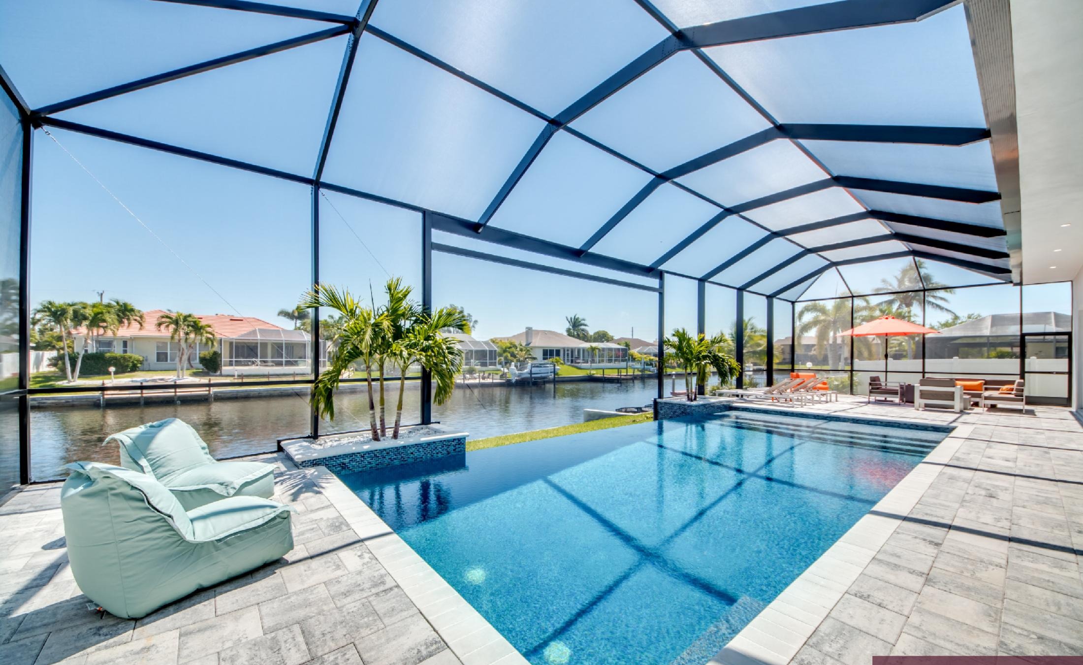 Moderner Salzwasser-Infinity-Pool mit Spa am Kanal, mit Bootsdock im Hintergrund.