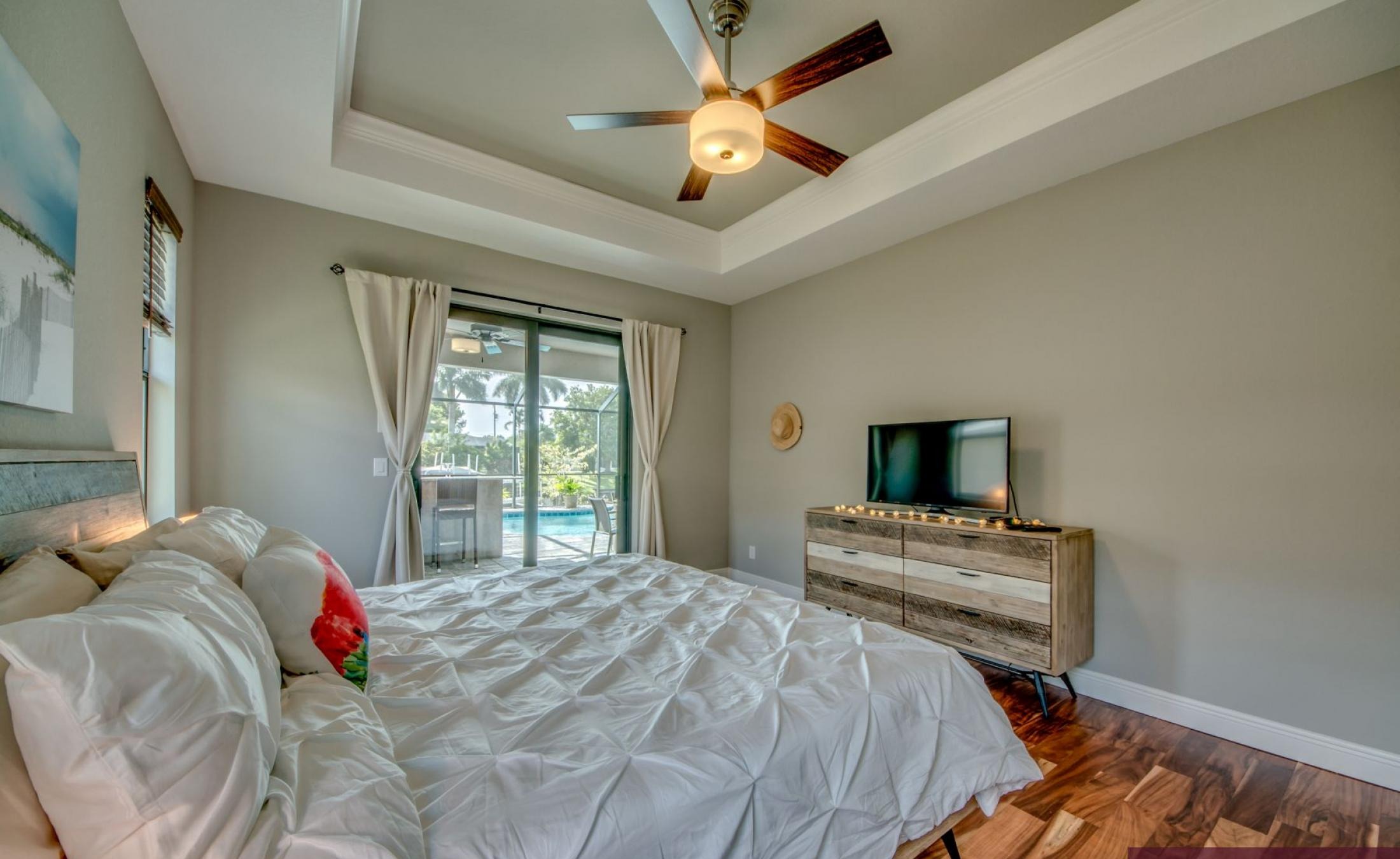 Sonnige Poolterrasse am Kanal mit Bootsdock und Blick aufs Wasser.