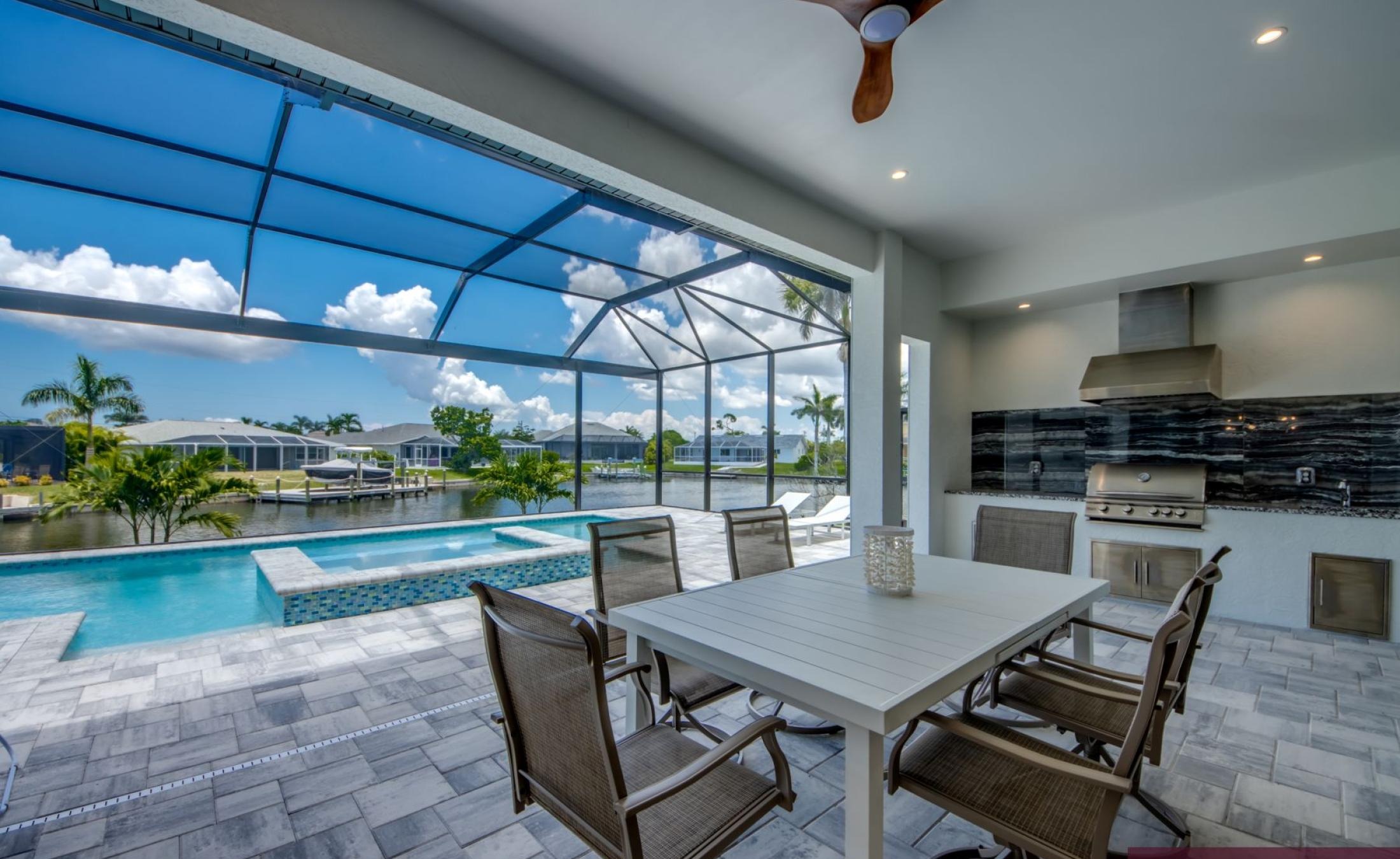 Pooldeck mit beheiztem Pool und Spa am Wasser, privates Dock im Hintergrund.