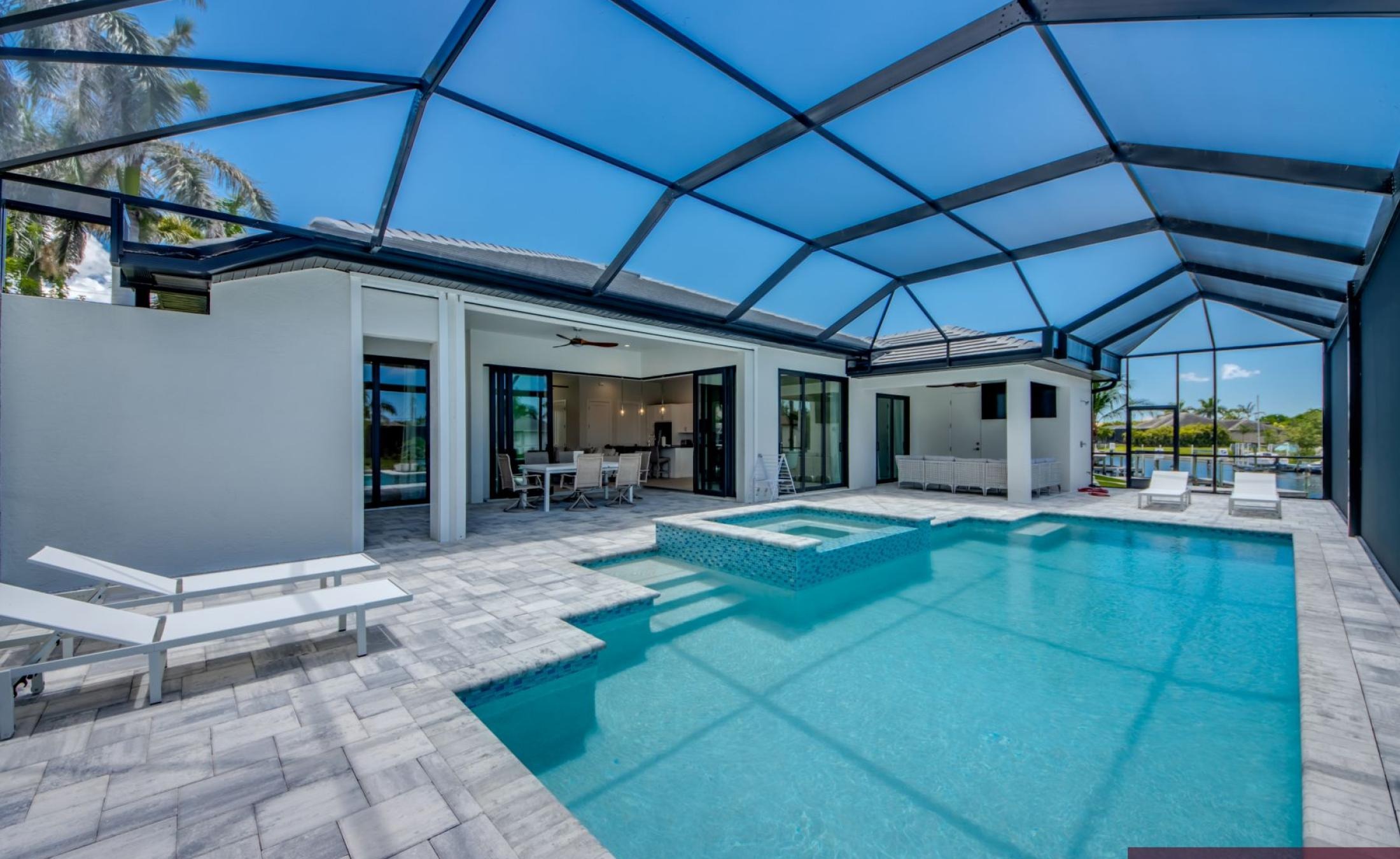 Pooldeck mit beheiztem Pool und Spa am Wasser, Blick auf den Kanal und privates Bootsdock.