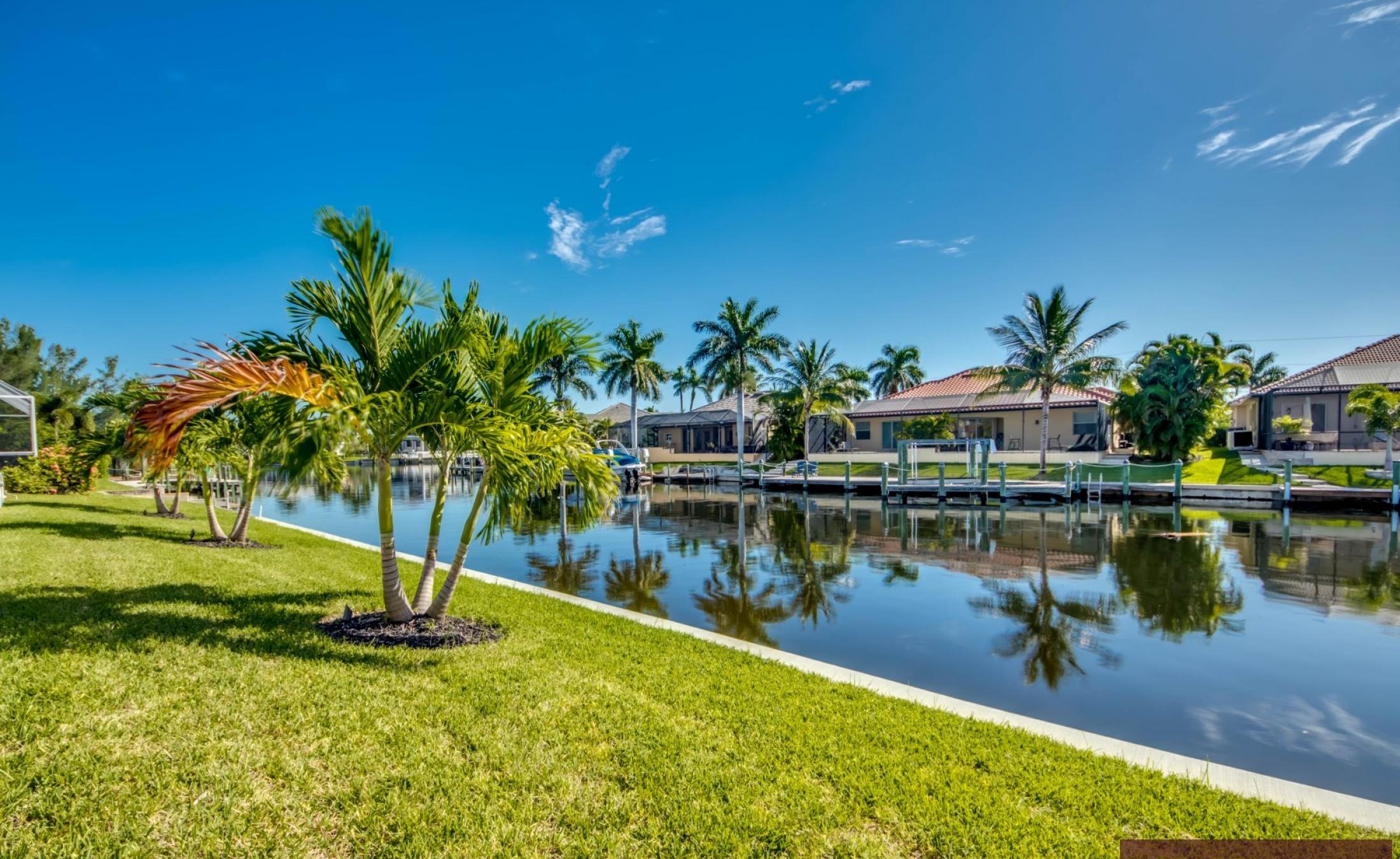 Privater Bootssteg mit Bootslift am Kanal, Blick auf Pool und Spa.