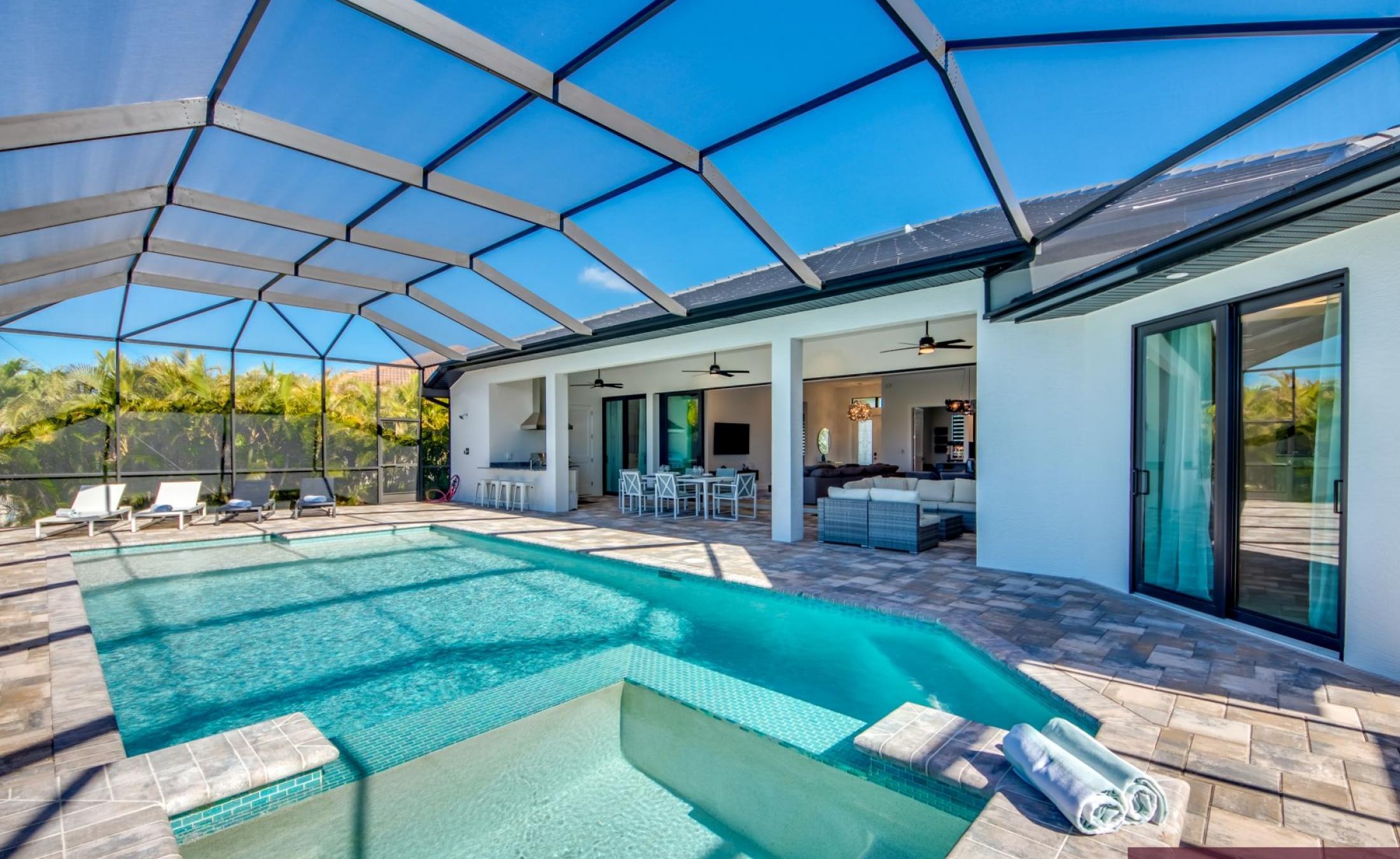 Sonnige Poolterrasse am Kanal mit Bootsdock und Sitzbereich.