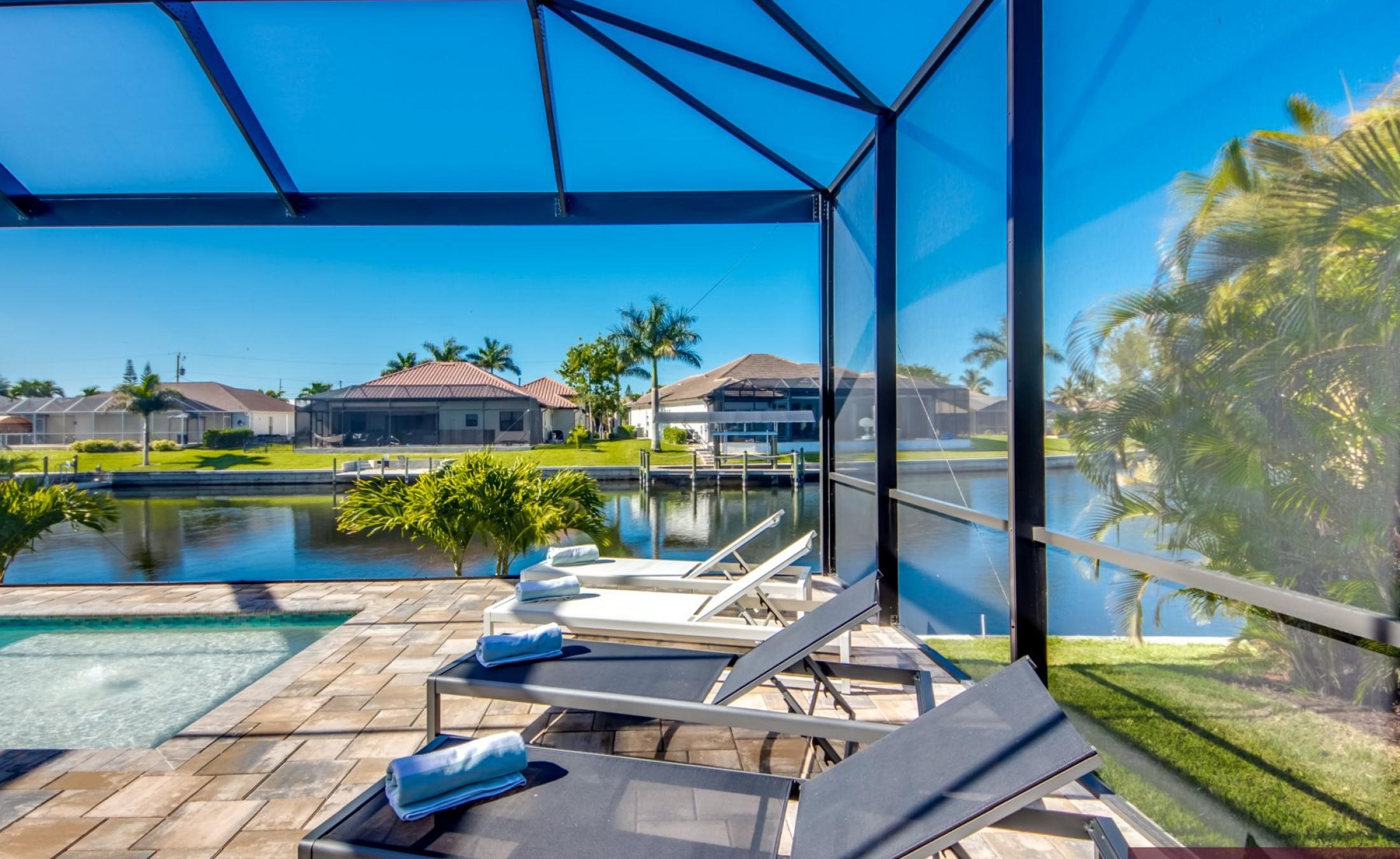 Poolbereich mit Sonnenliegen und Blick auf den Kanal.