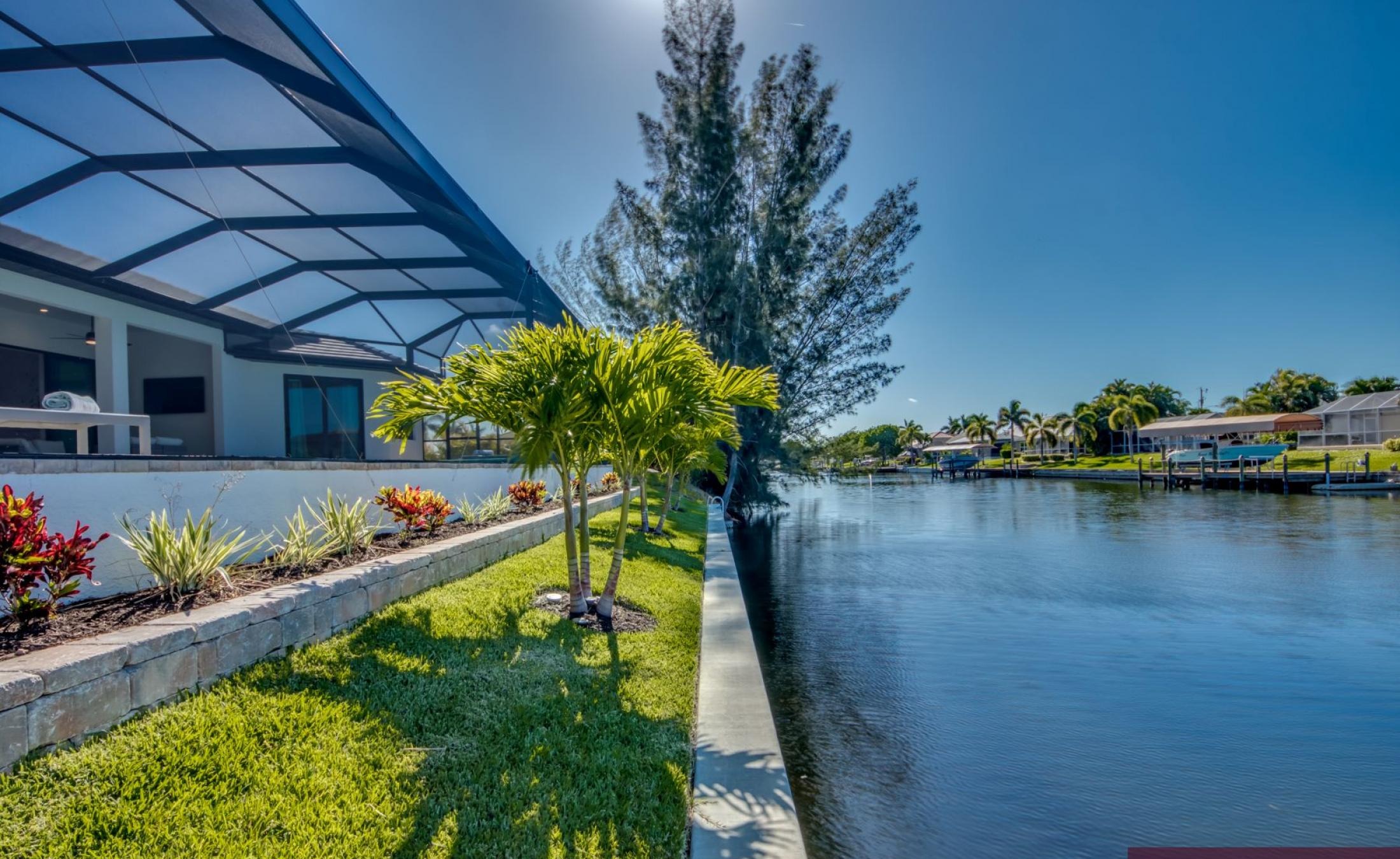 Sonnige Poolterrasse am Kanal mit Bootsdock und Liegen.