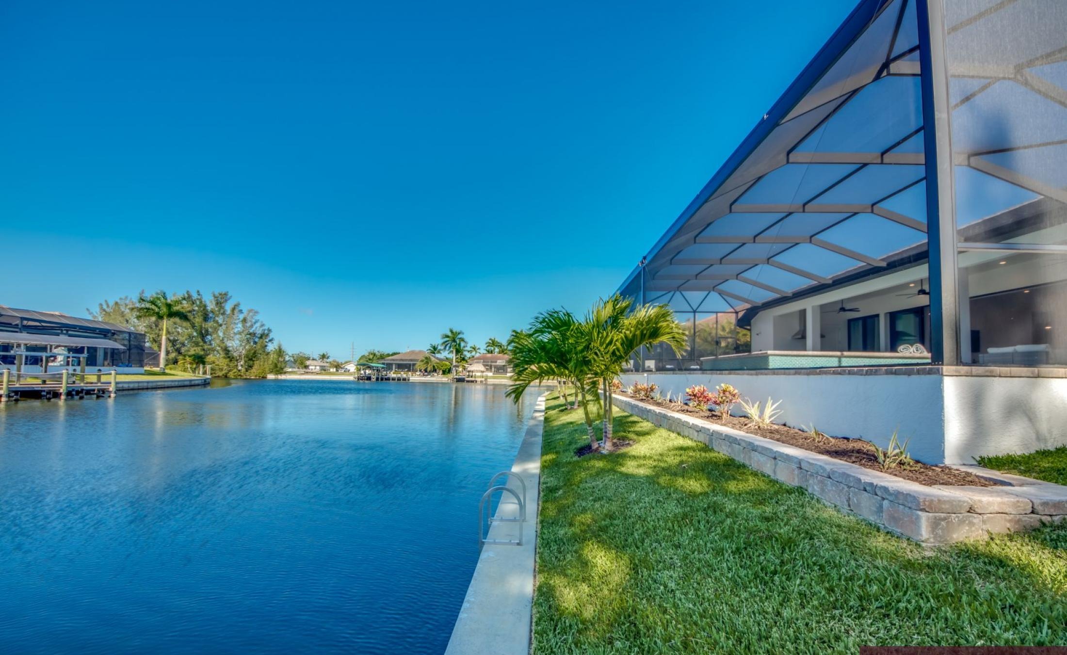 Sonnige Poolterrasse am Kanal mit Dock und Sitzbereich.