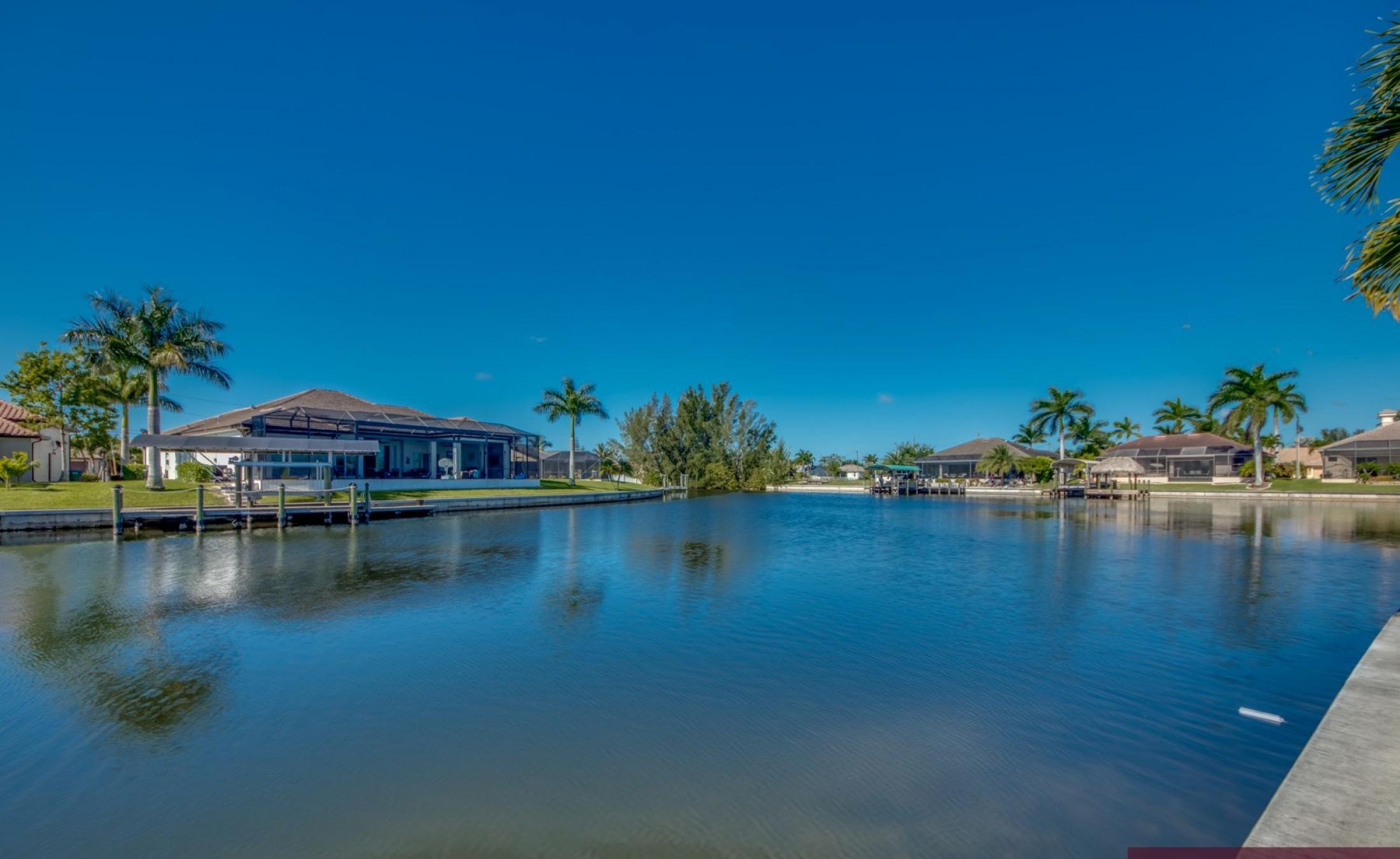 Sonnige Poolterrasse mit Blick auf den Kanal und Bootsdock.