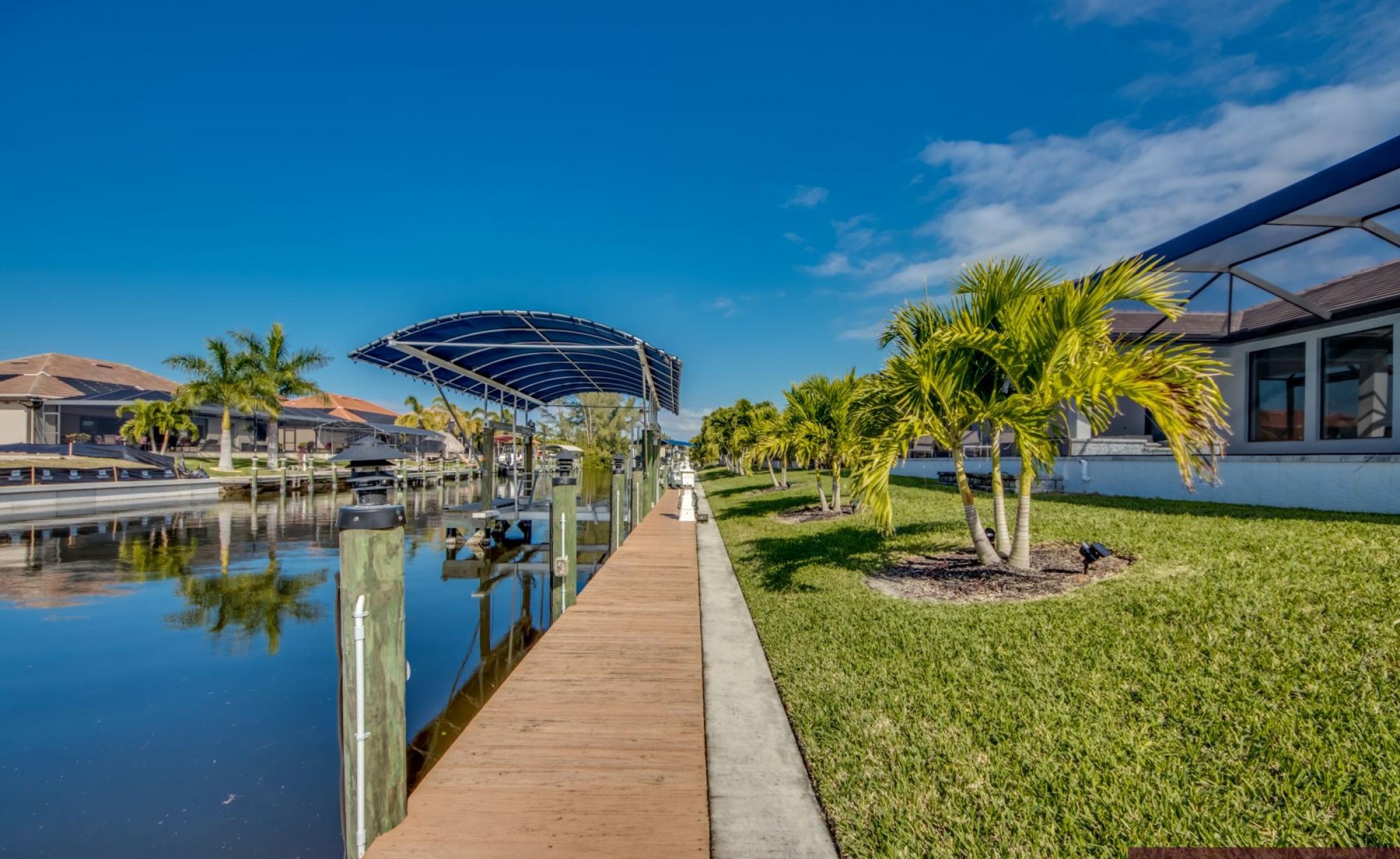 Privates Bootsdock mit Bootslift am Kanal bei Sonnenuntergang.