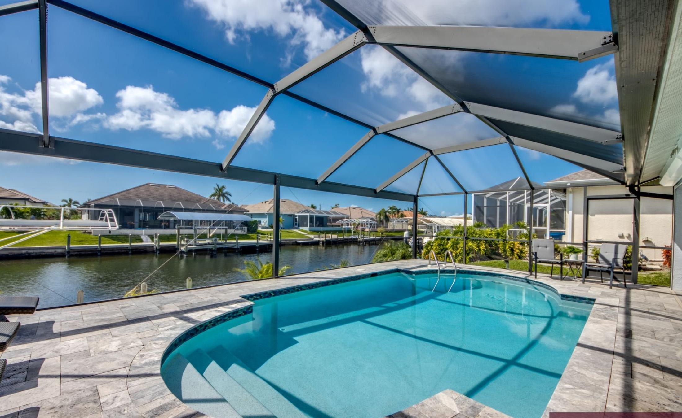 Sonniges Pooldeck mit beheiztem Pool und Blick auf den Kanal mit Bootsdock.