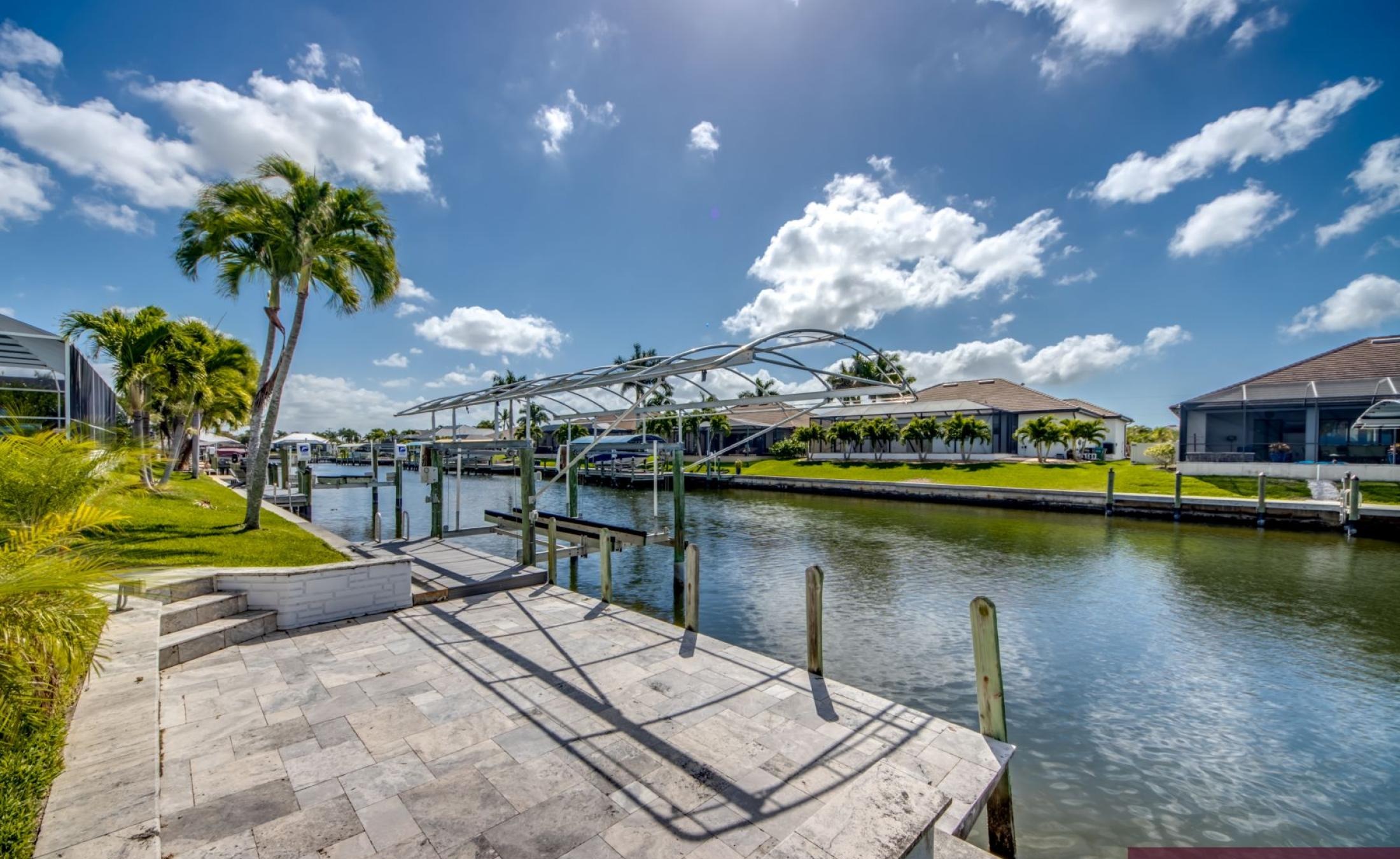 Sonniges Pooldeck mit beheiztem Pool und Blick auf den Kanal mit Bootsdock.