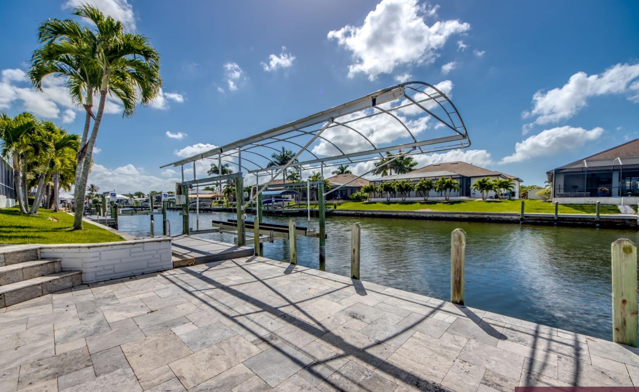 Sonniges Pooldeck mit beheiztem Pool und Blick auf den Kanal mit Bootsdock.