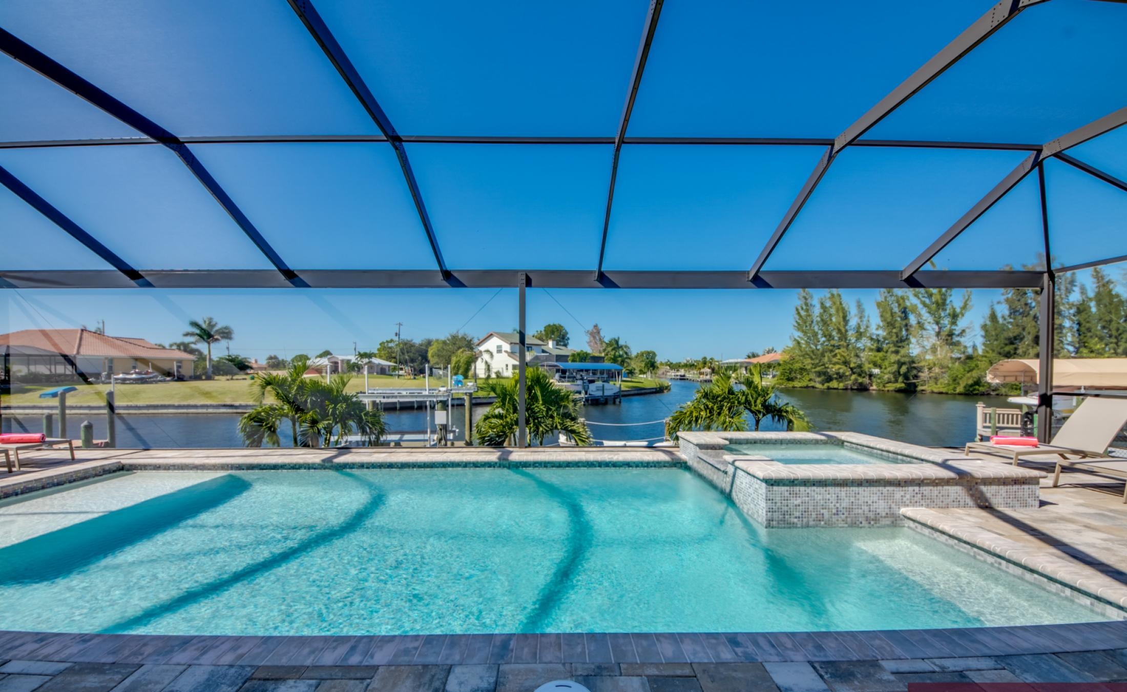 Moderner Pool mit Spa und Blick auf den Kanal bei Sonnenuntergang.