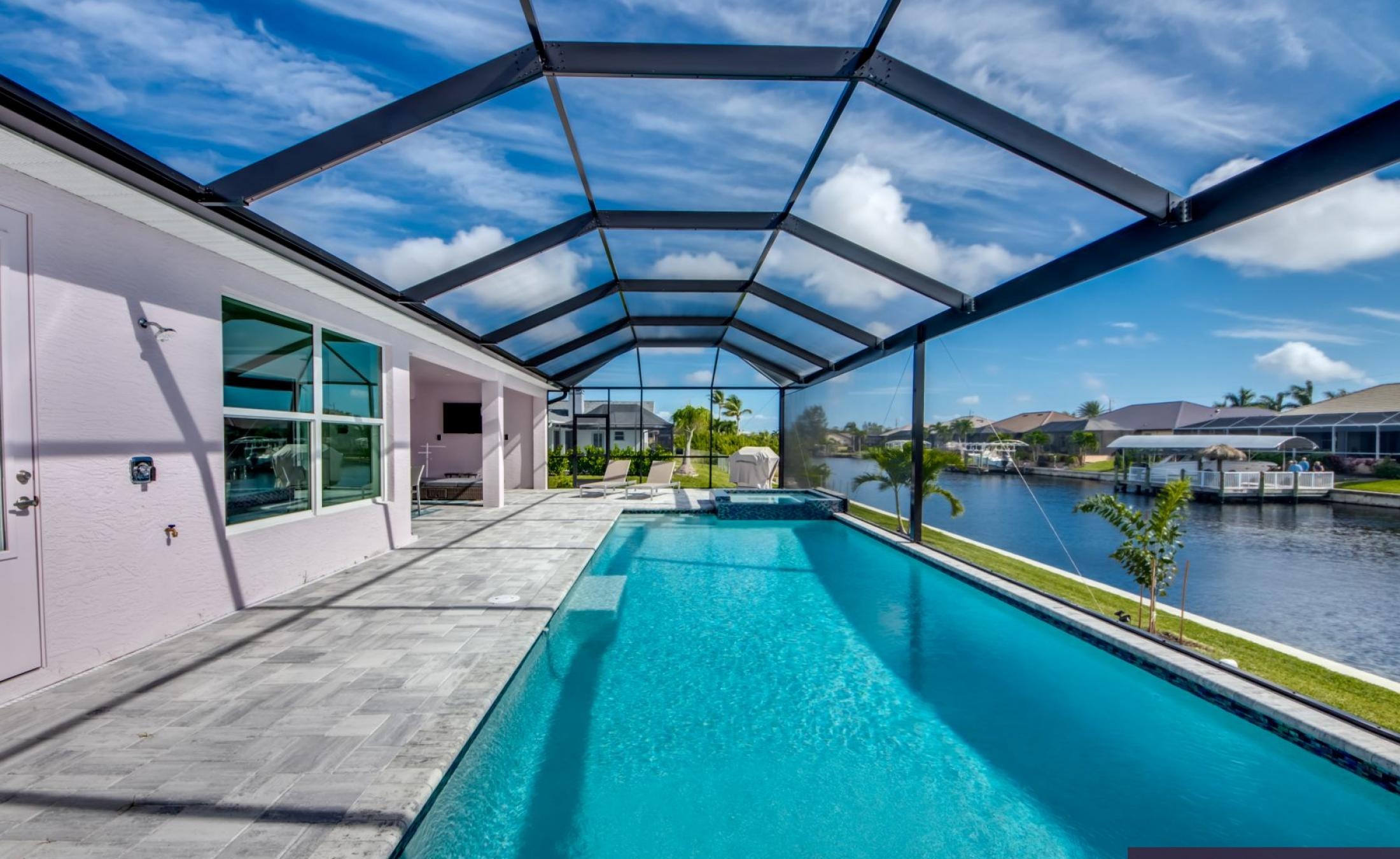 Moderner Pool- und Lanai-Bereich mit Blick auf den Kanal und Bootsanleger.