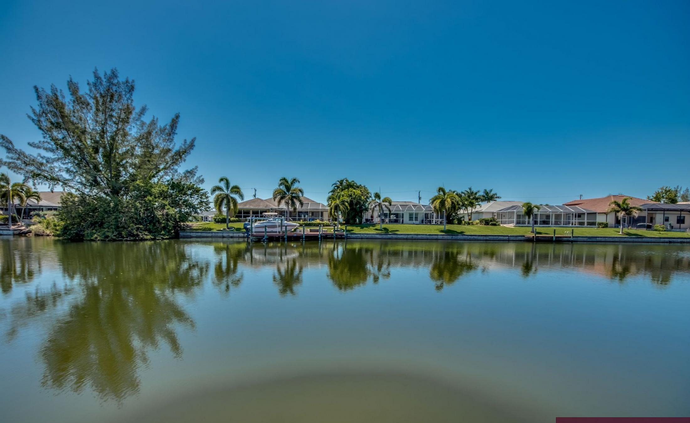 Sonniger Poolbereich am Kanal mit privatem Bootsdock und Blick aufs Wasser.