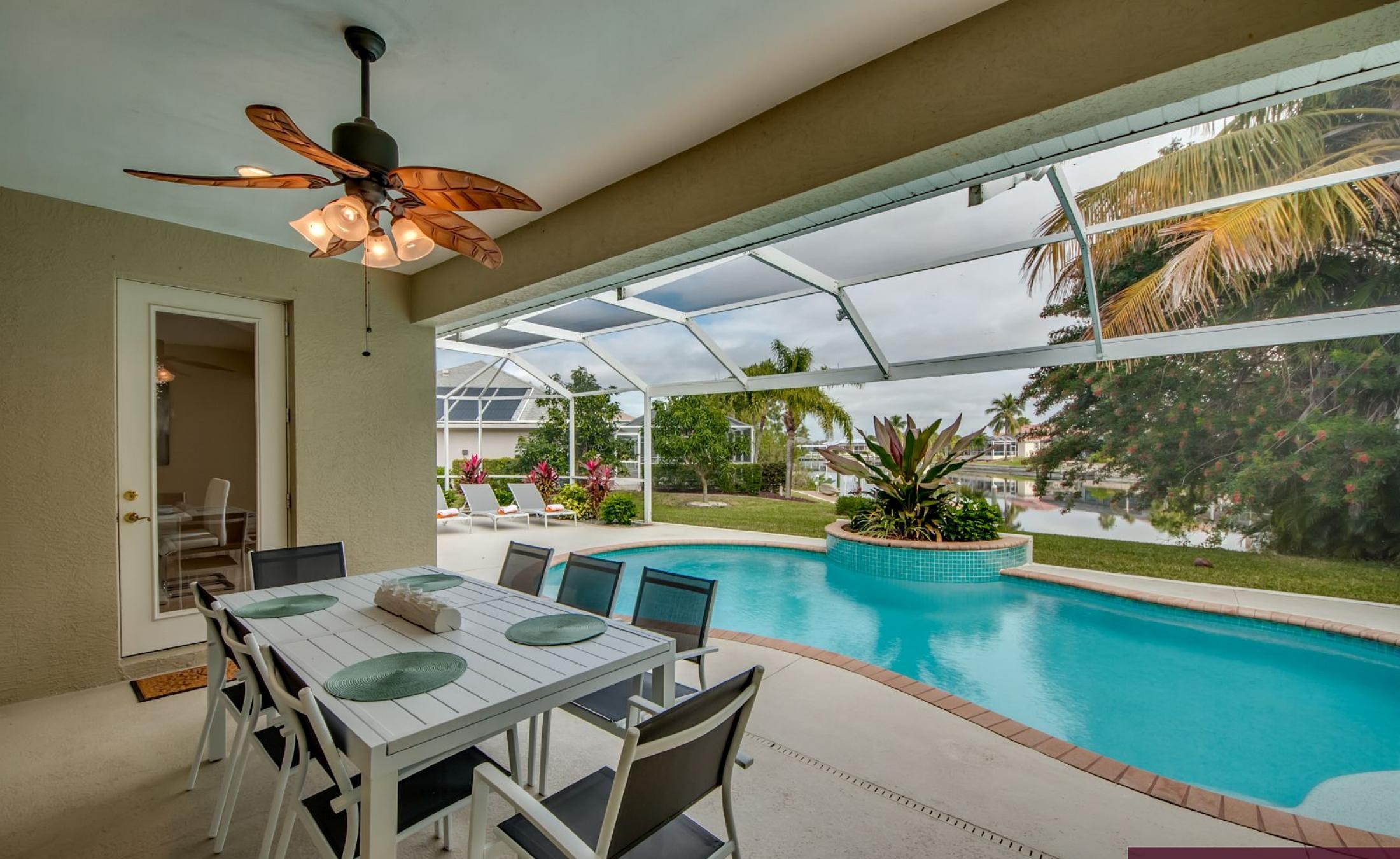 Elektrisch beheizter Pool mit Sonnenschirm und Strandstühlen am Wasserkanal.